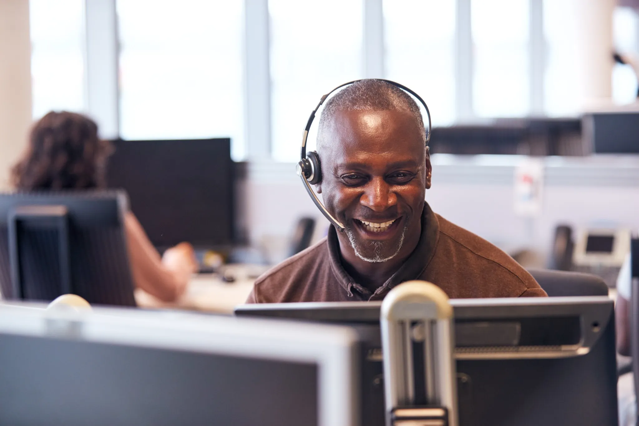 Friendly man with headset looking at computer screen