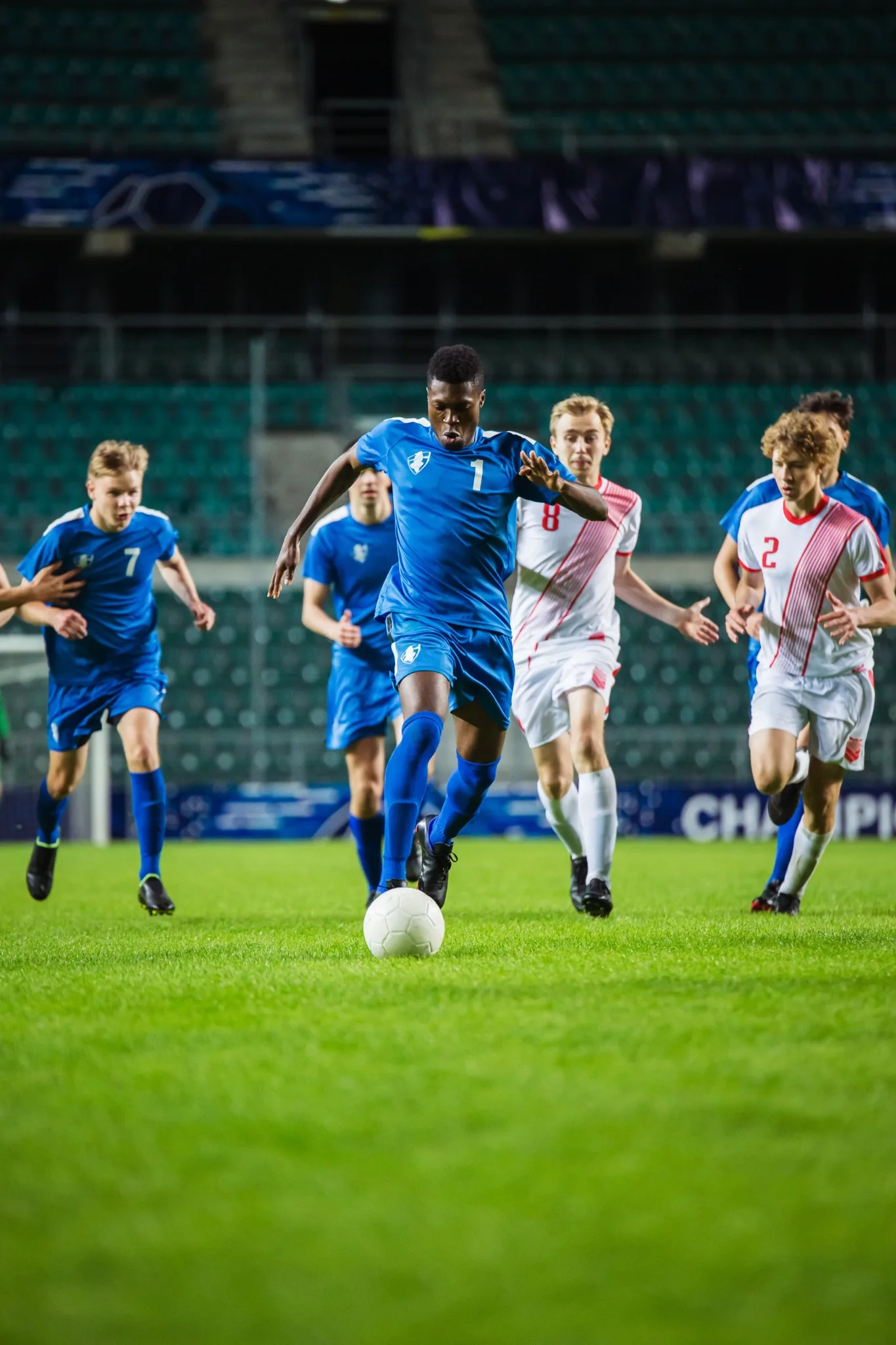 Soccer players running across the field chasing a ball