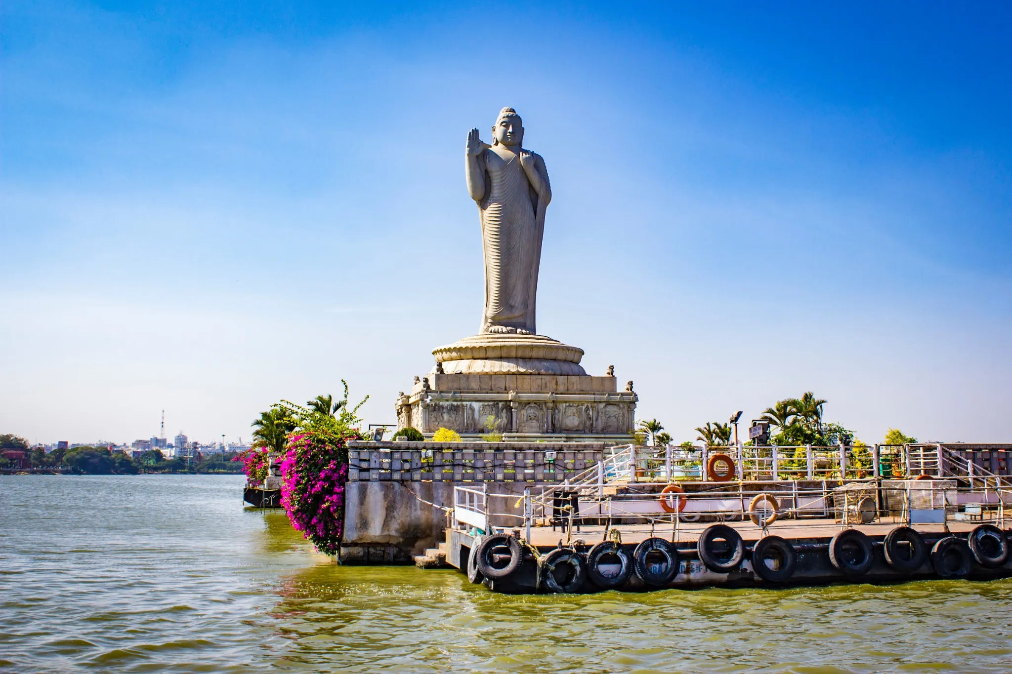 Sailing by the Giant Buddha Statue with Bright Pink Bougainvillea Plants in the Middle of Hussain Sagar Lake in Hyderabad, India
