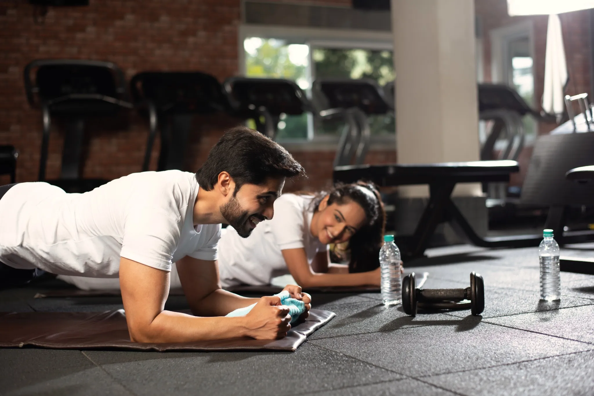 Indian asian young couple doing Plank exercise in gym.