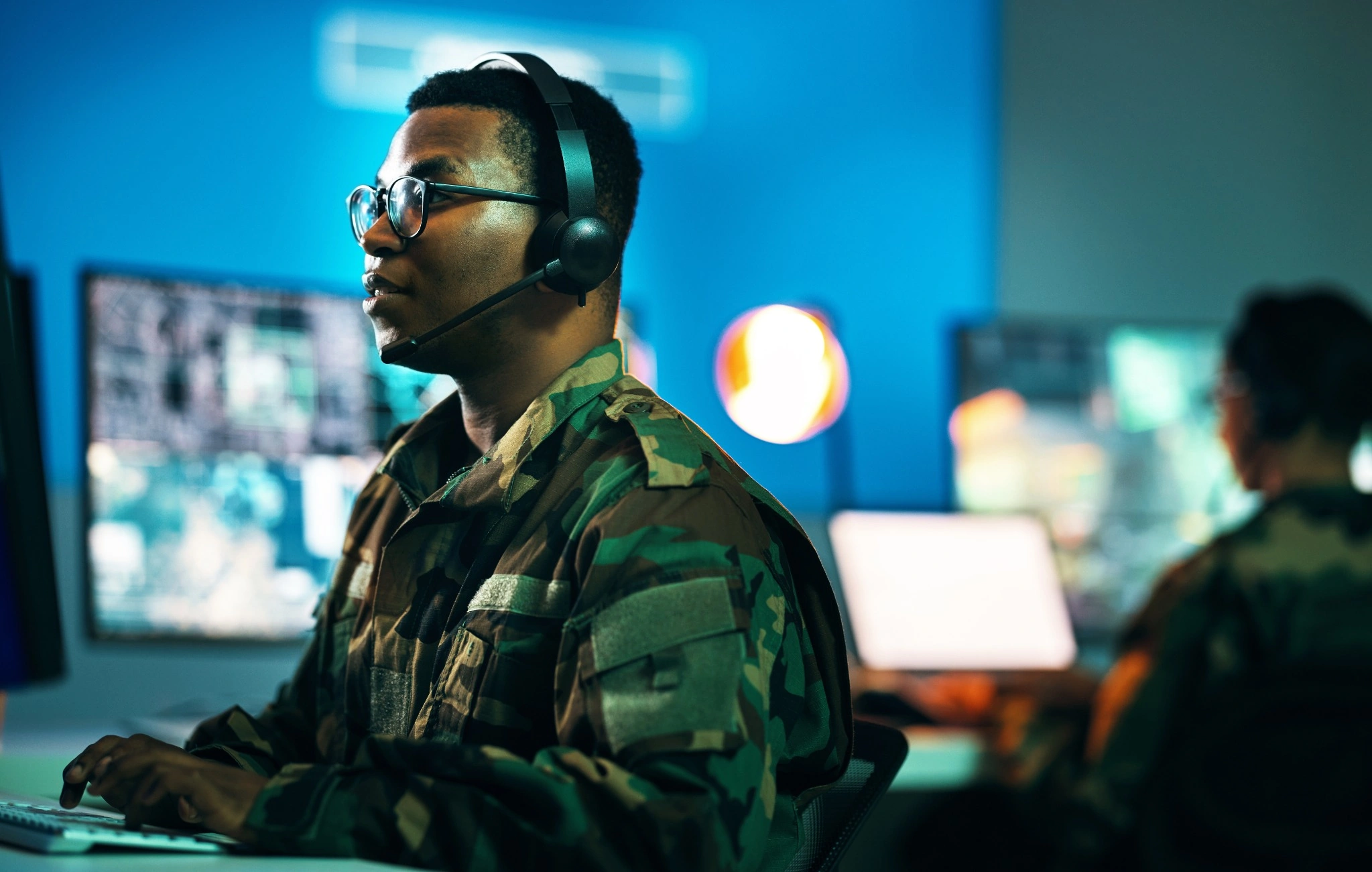Army, control room and man on computer in office, data center and monitor for technical support, cybersecurity or surveillance.