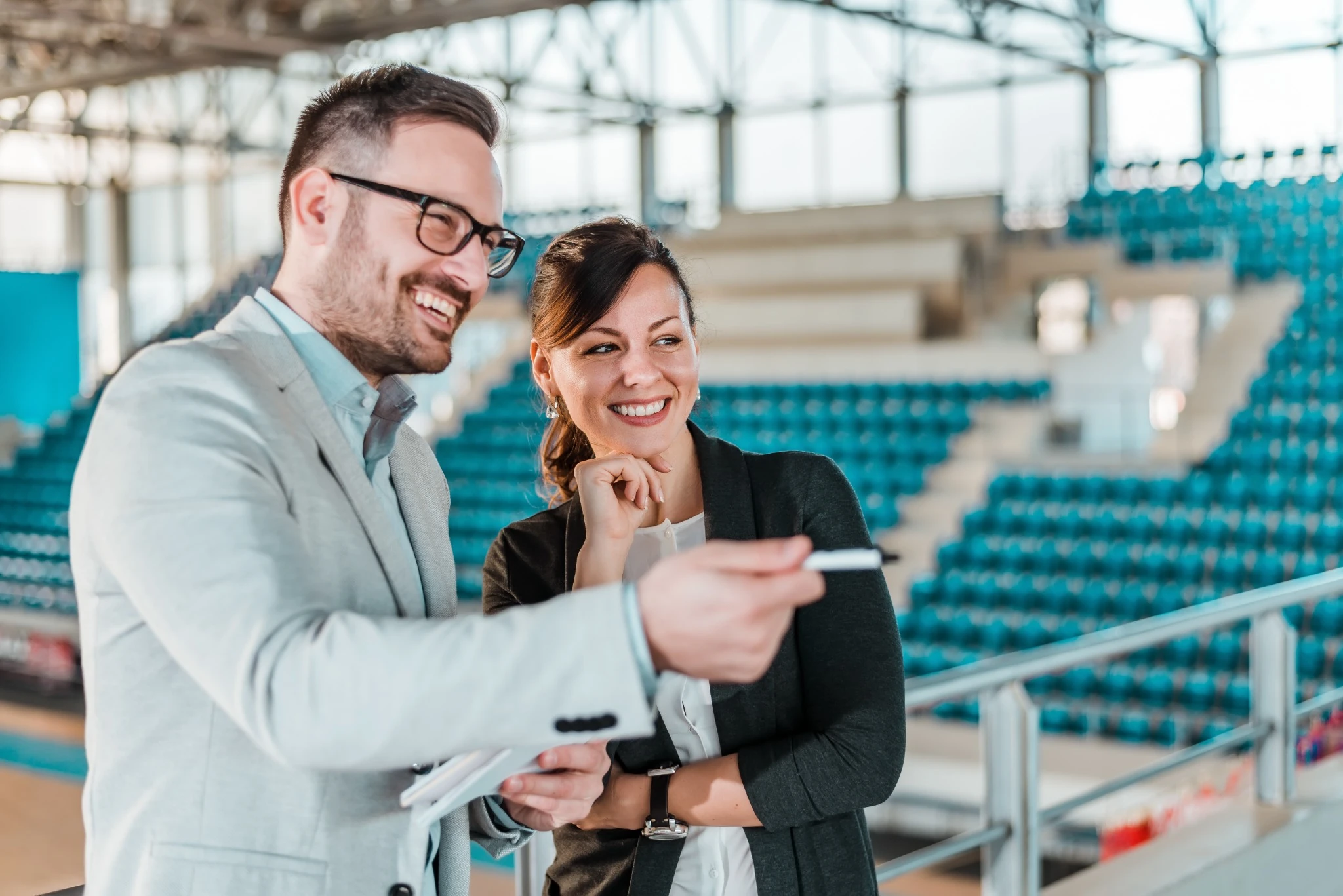 two people in business attire at empty basketball court smiling