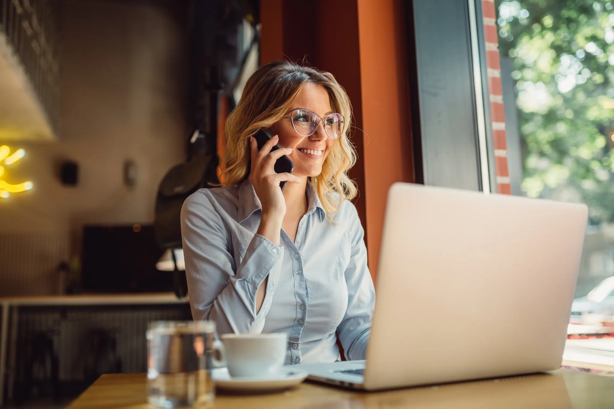 Woman sitting in front of laptop talking on phone