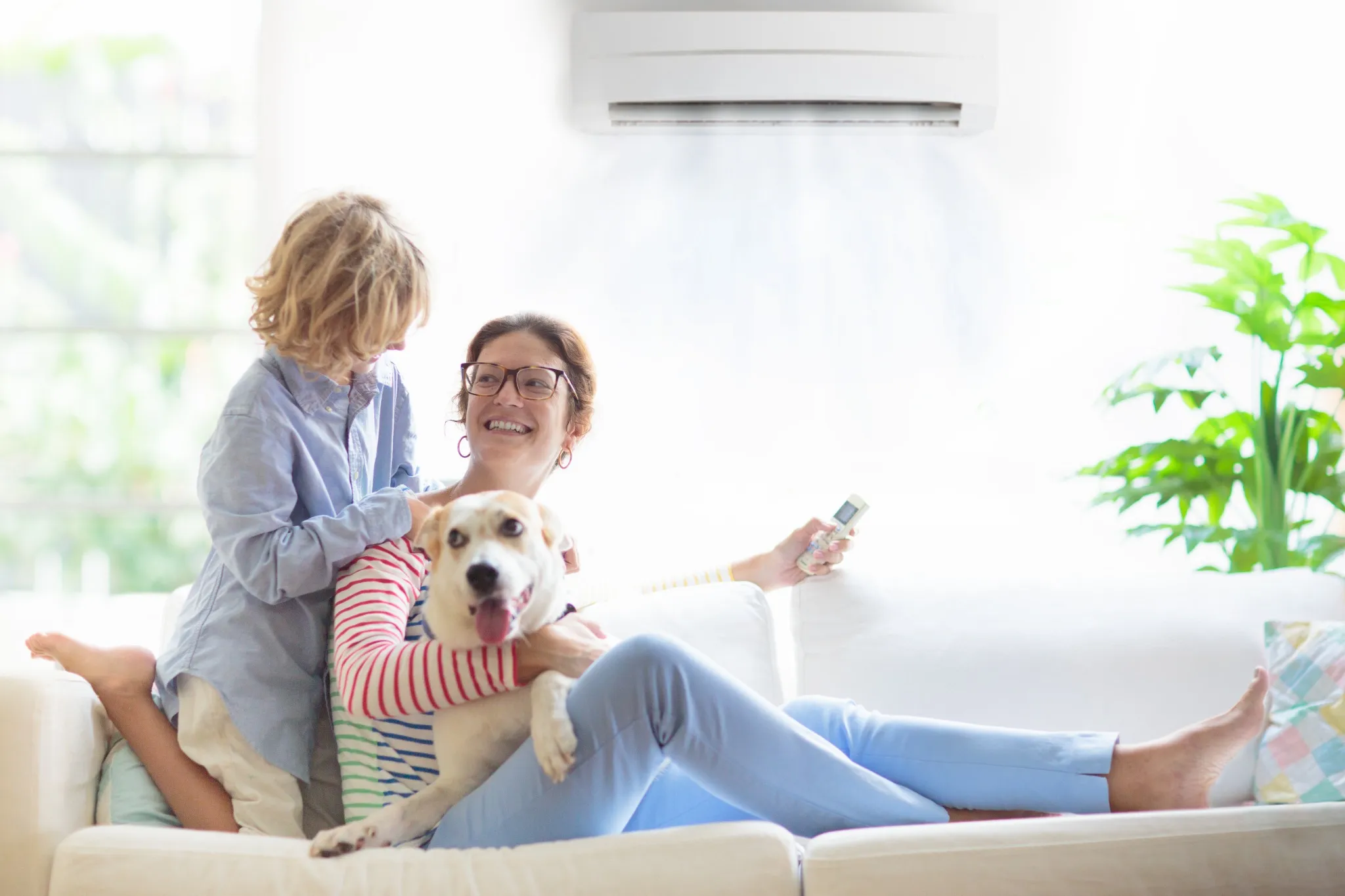 Mother and child with air conditioner remote and dog