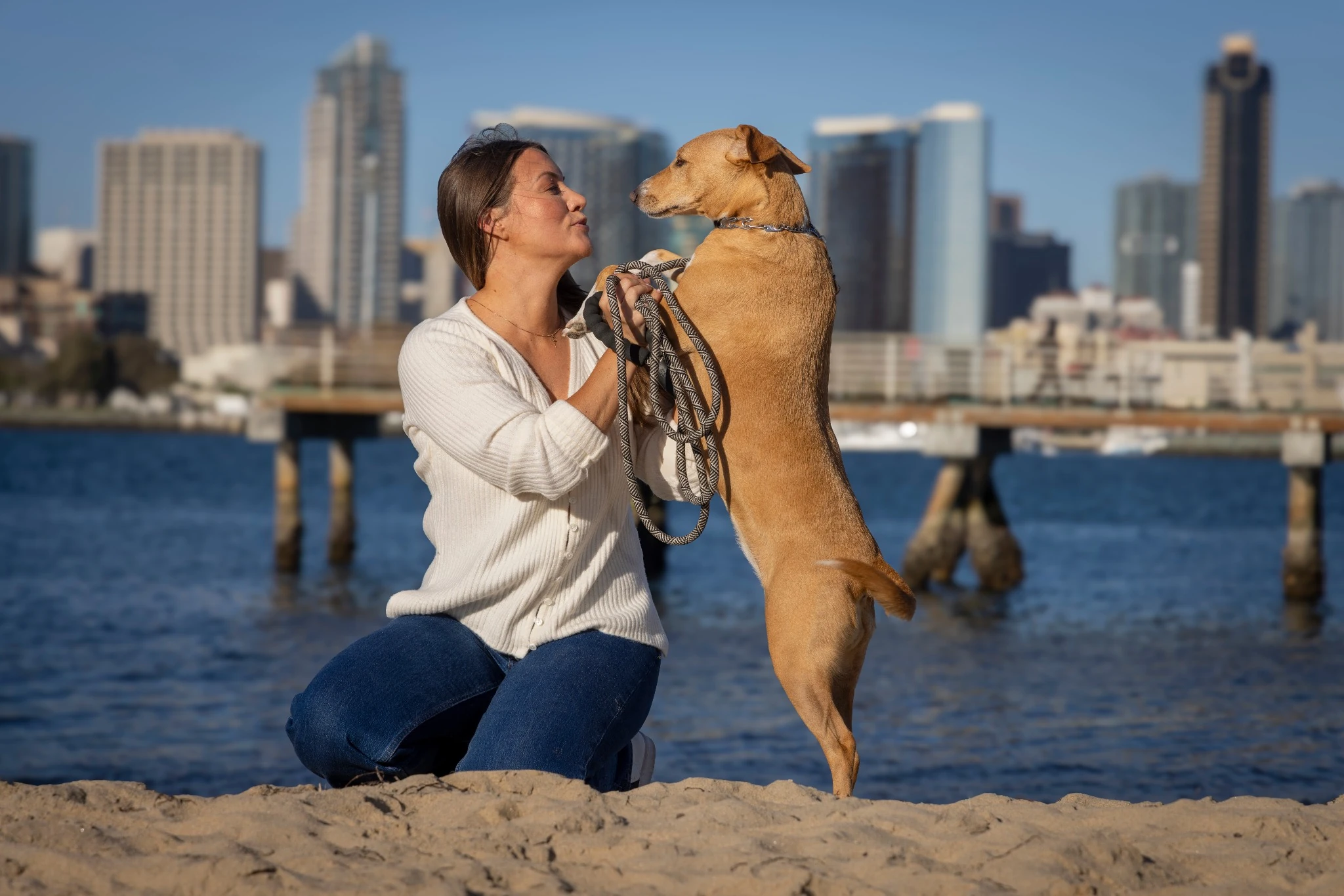 woman playing with brown dog downtown san diego in background