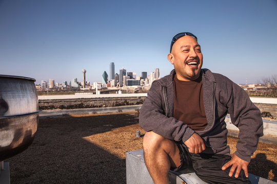 Laughing man sitting on a rooftop