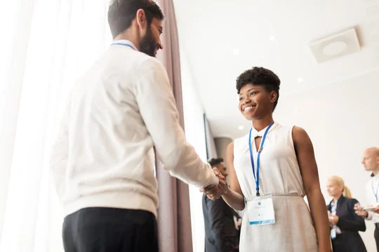 smiling woman shaking hands with a man at a business conference