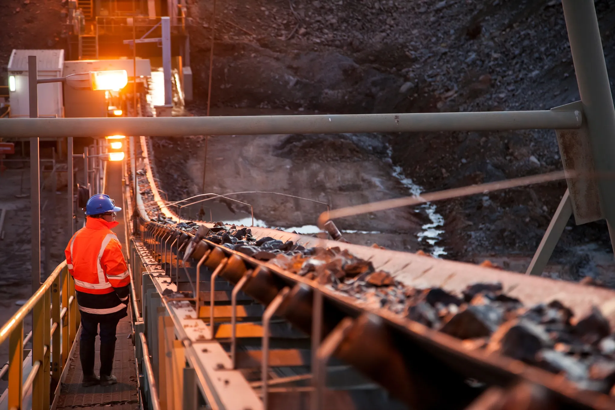Shallow depth of field image of a miner inspecting ore rocks on a conveyor