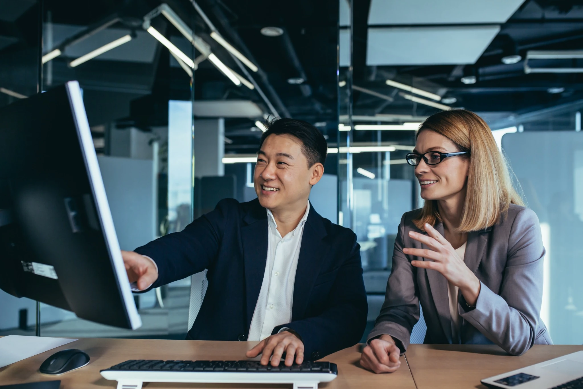 Happy and successful workers looking at computer monitor, Asian man and woman working in modern office.