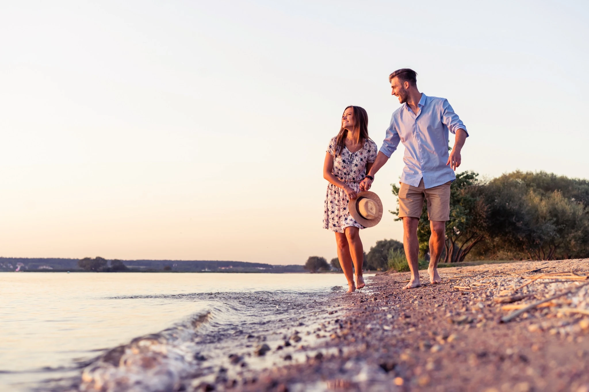 Couple walking on the beach at sunset.