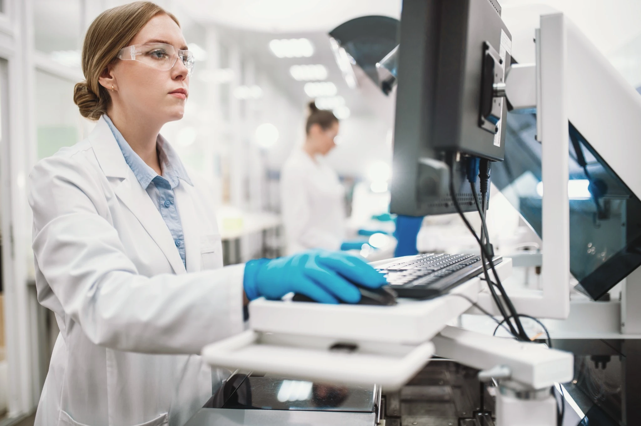A team of laboratory technicians conduct a series of tests on a chemical analyzer in a biological laboratory.