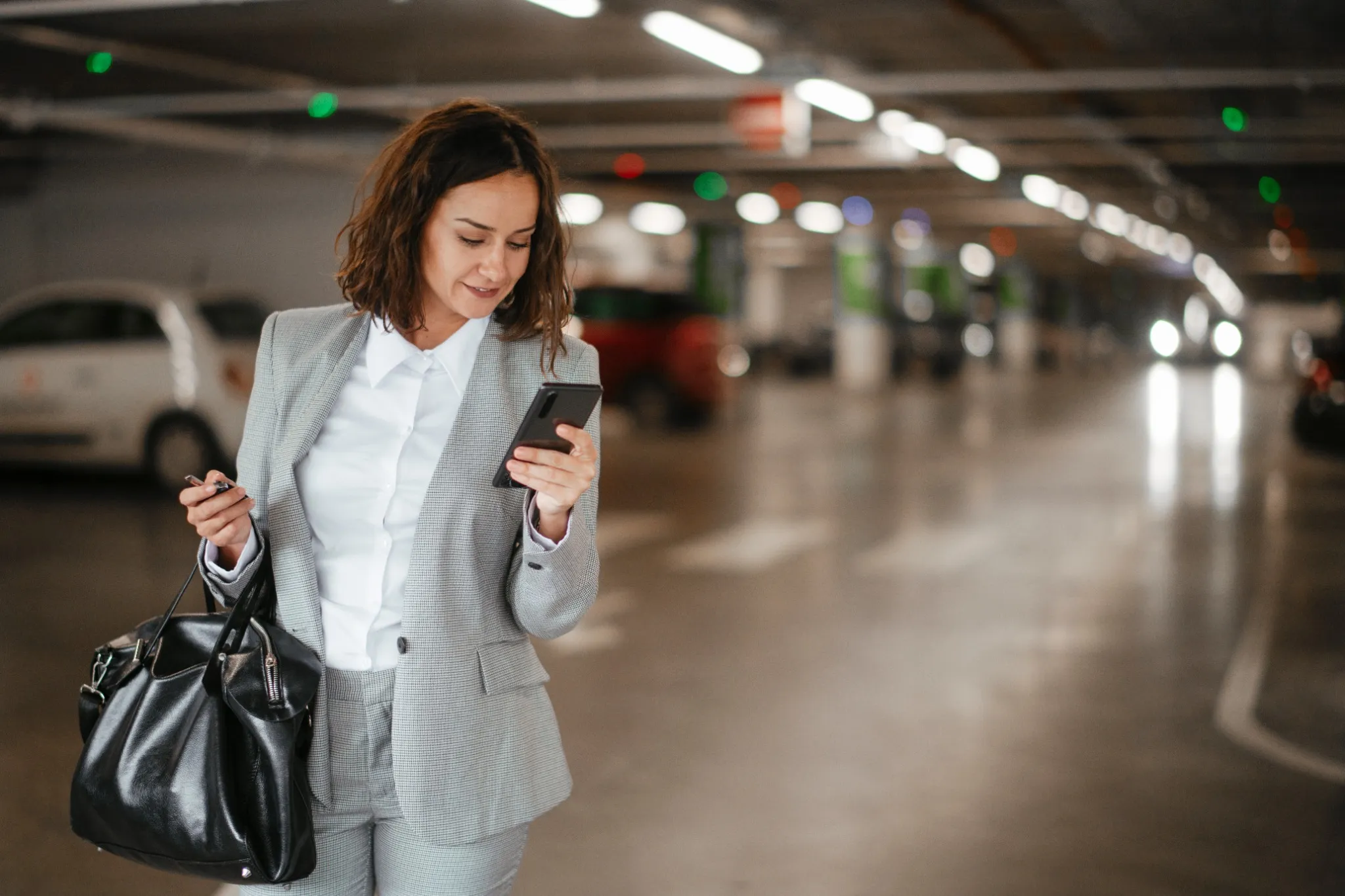 Young businesswoman using phone in garage.