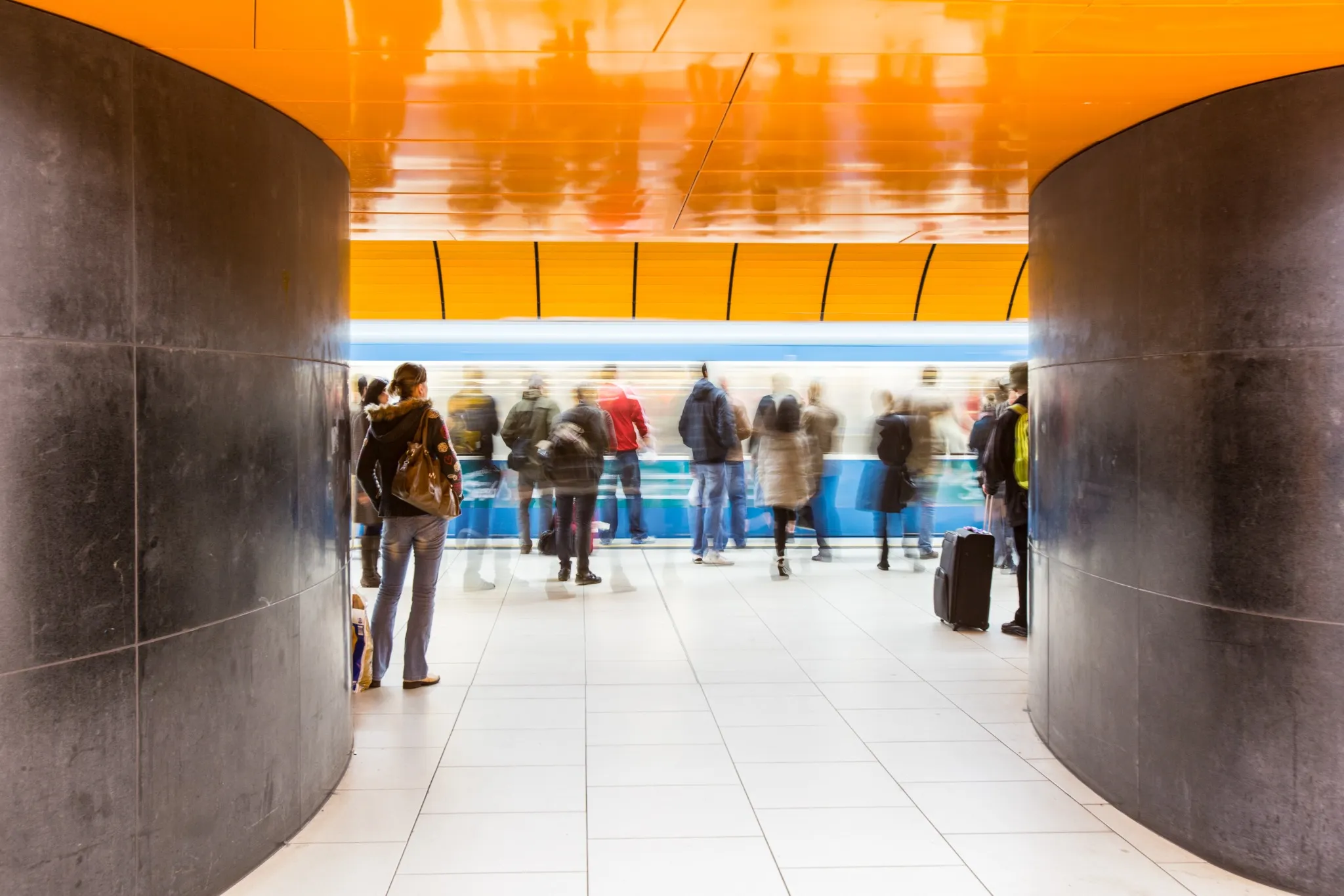 People rushing through a subway corridor (motion blur technique is used to convey movement).