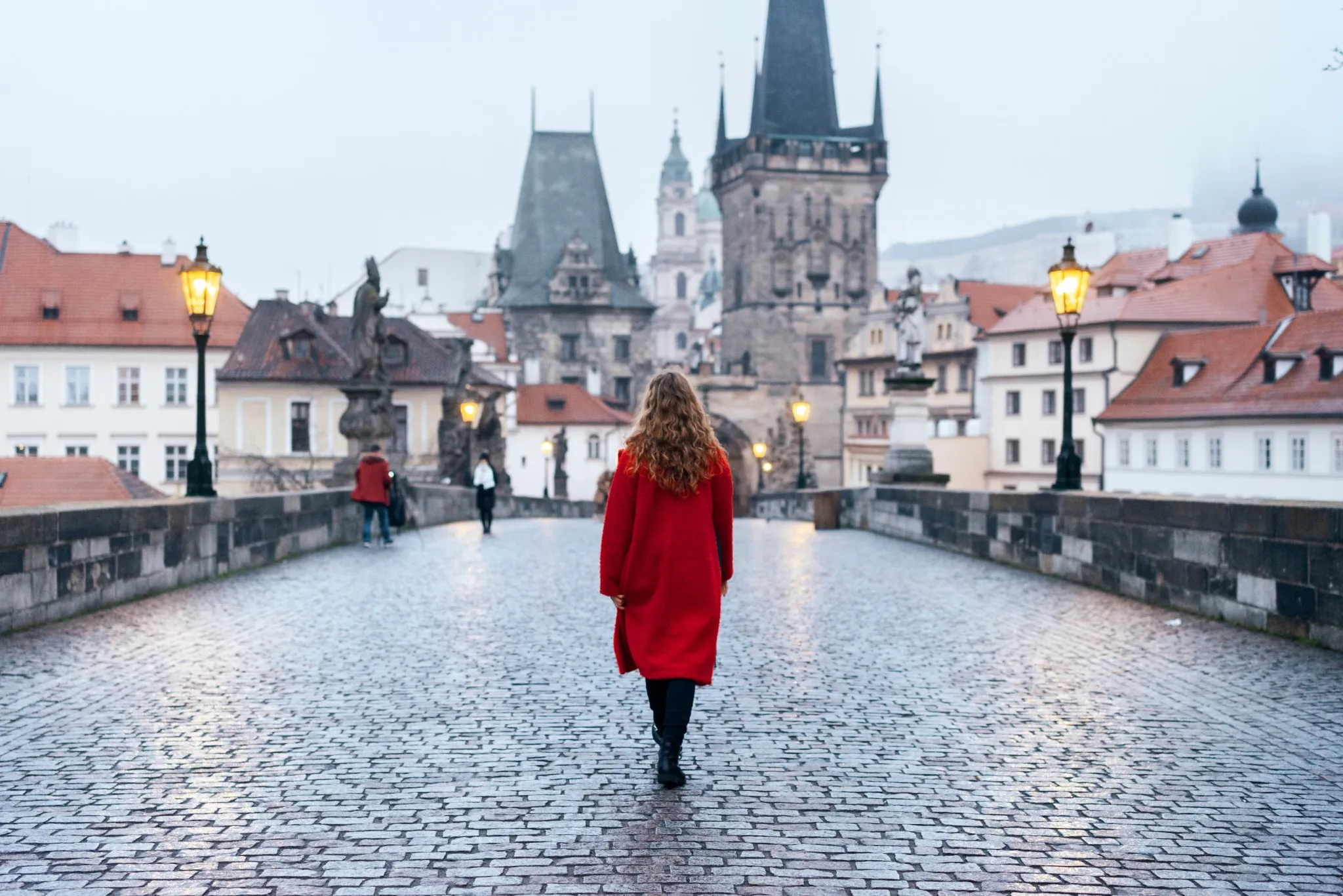 Female tourist walking alone on the Charles Bridge during the early morning in Prague, capital of Czech Republic