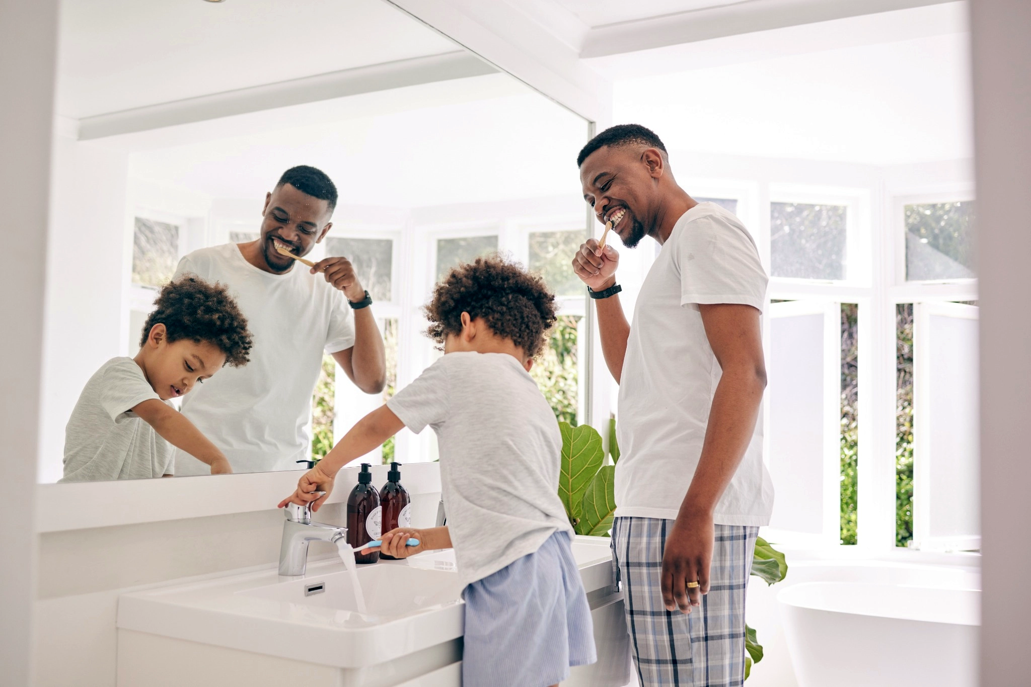 Father and son having fun brushing their teeth in the bathroom