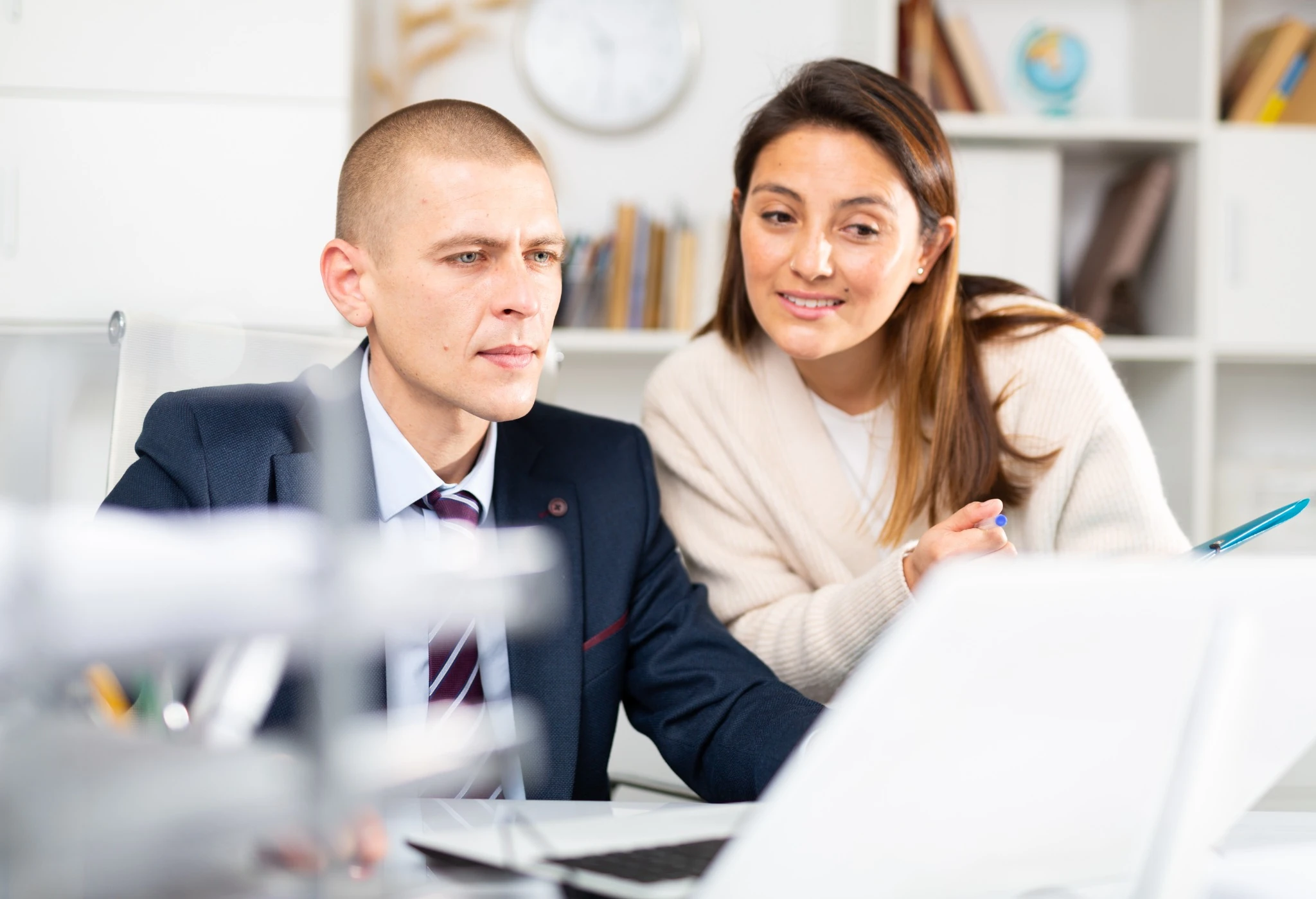 American businessman using laptop while discussing something with colleague at white office.