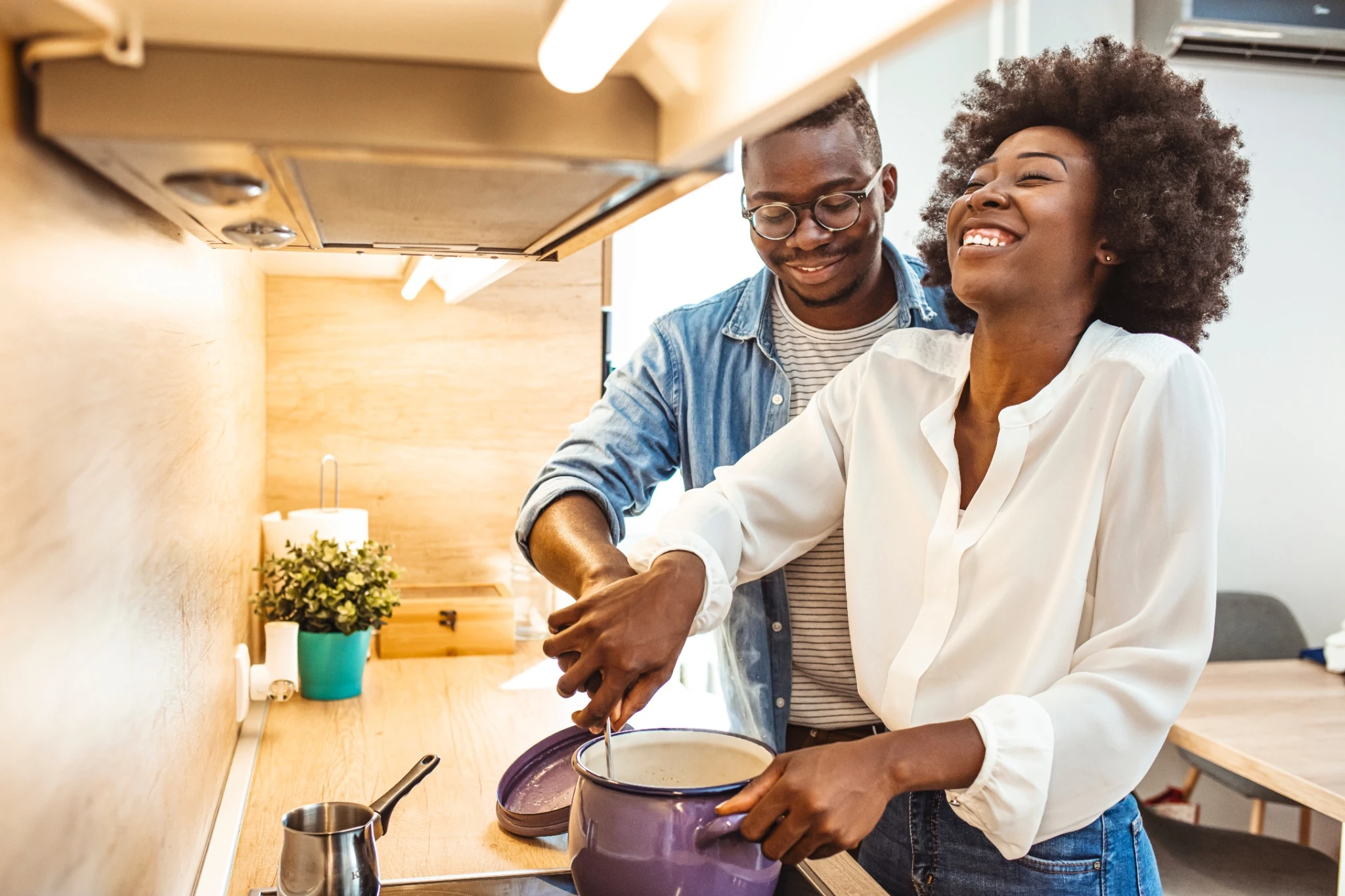 couple laughing while cooking together over stovetop