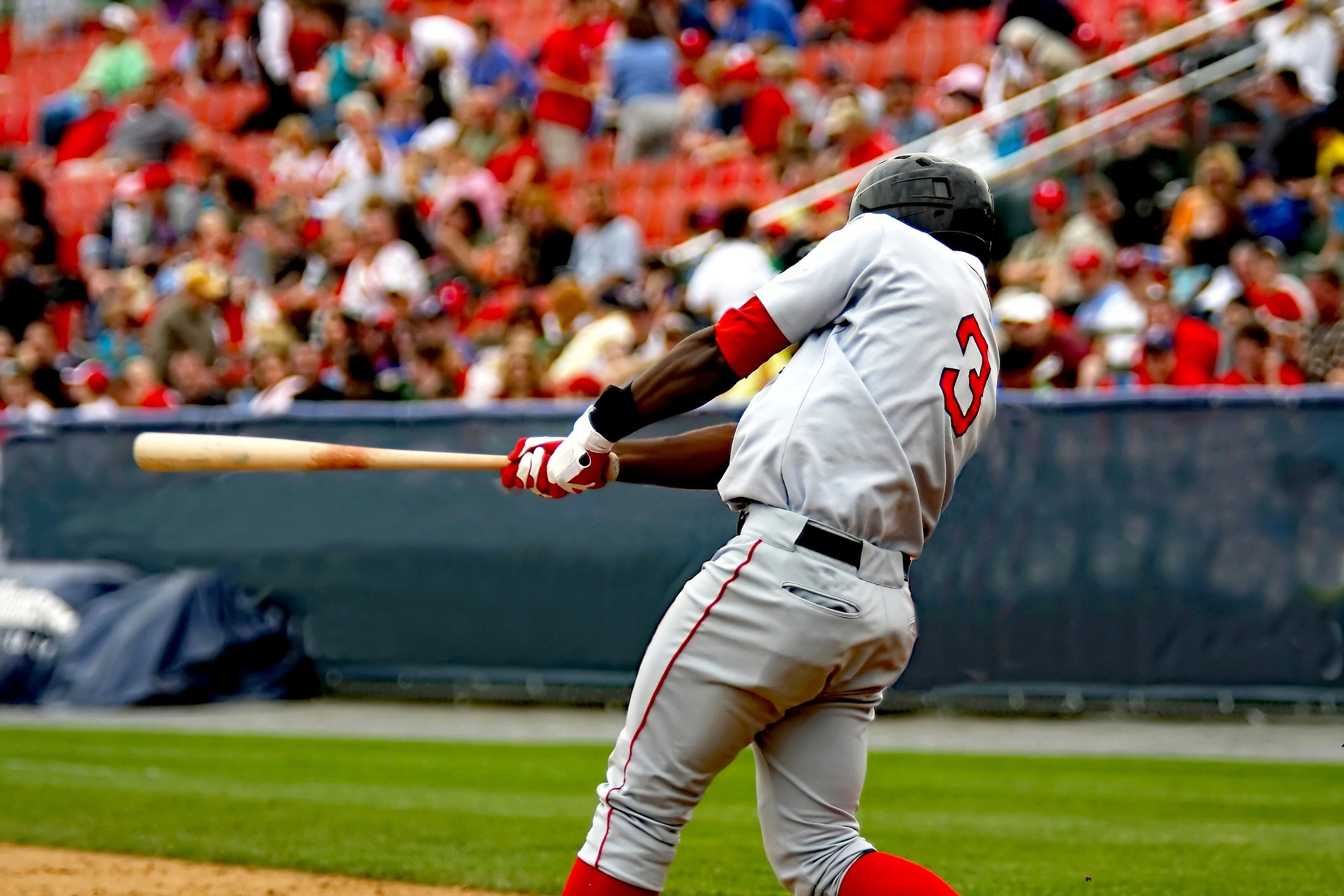 Baseball player swinging through hit in front of a crowd