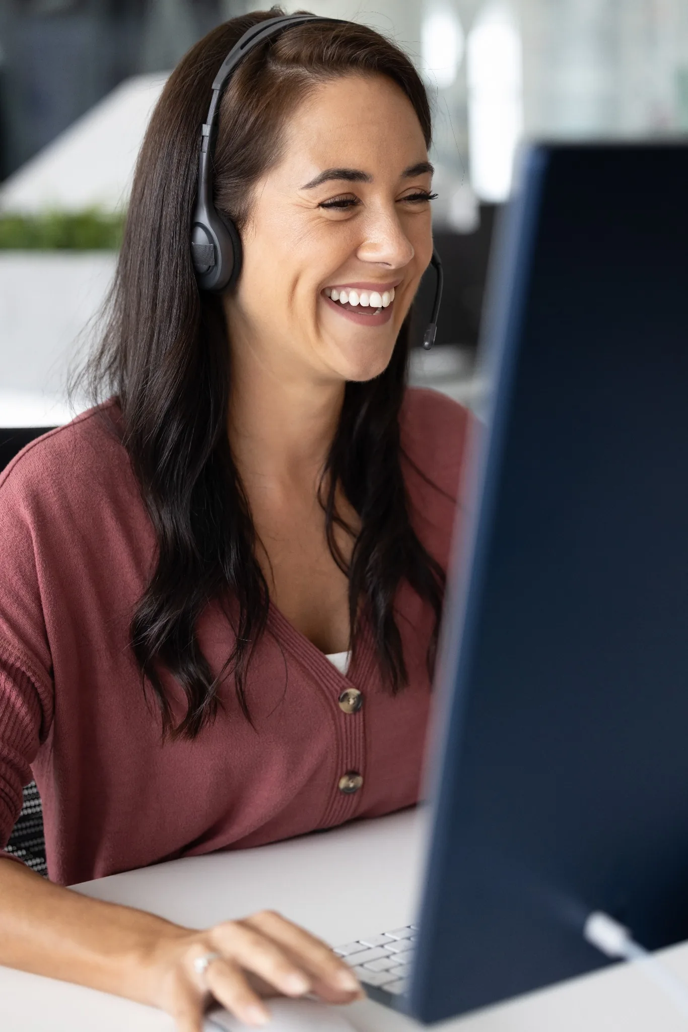 Woman with headset on smiling at computer