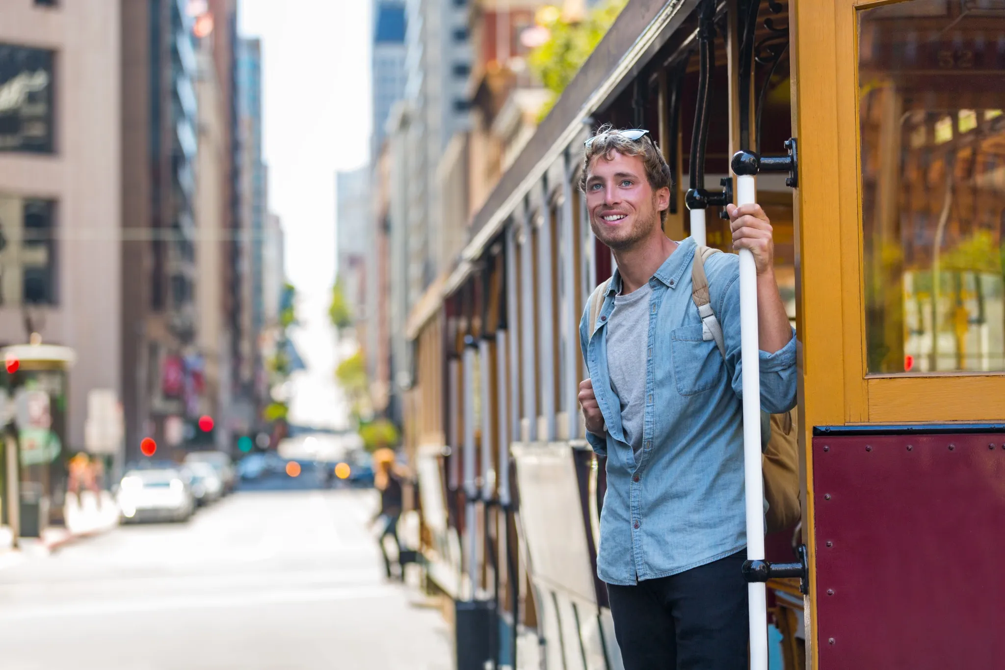 San Francisco man riding cable car tramway. Young casual guy in his 20s using public transport system in the city to travel to work or university. 