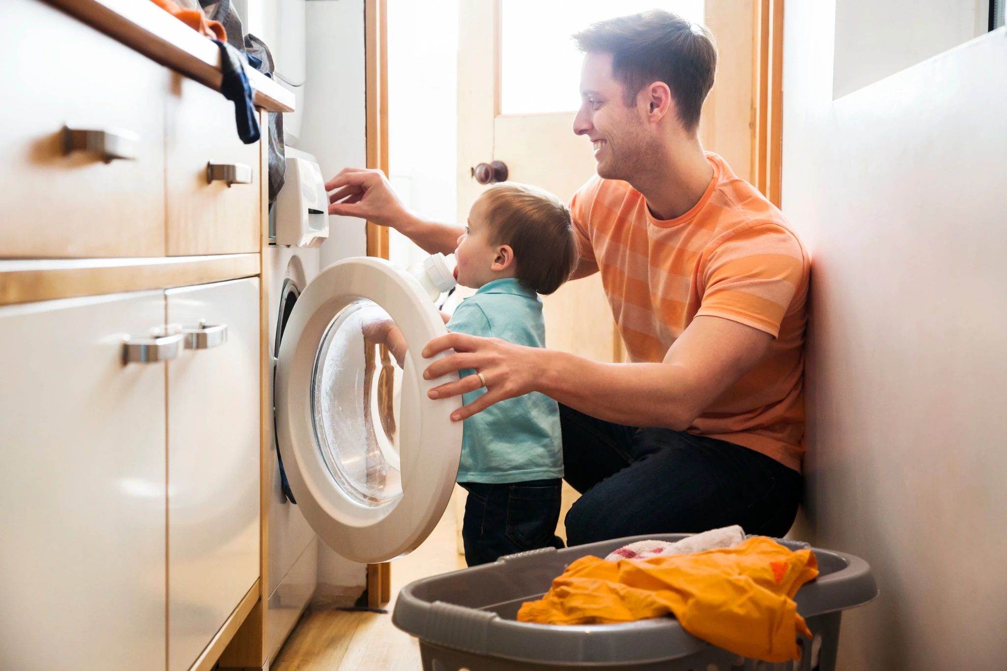 Father and toddler son doing laundry at home.