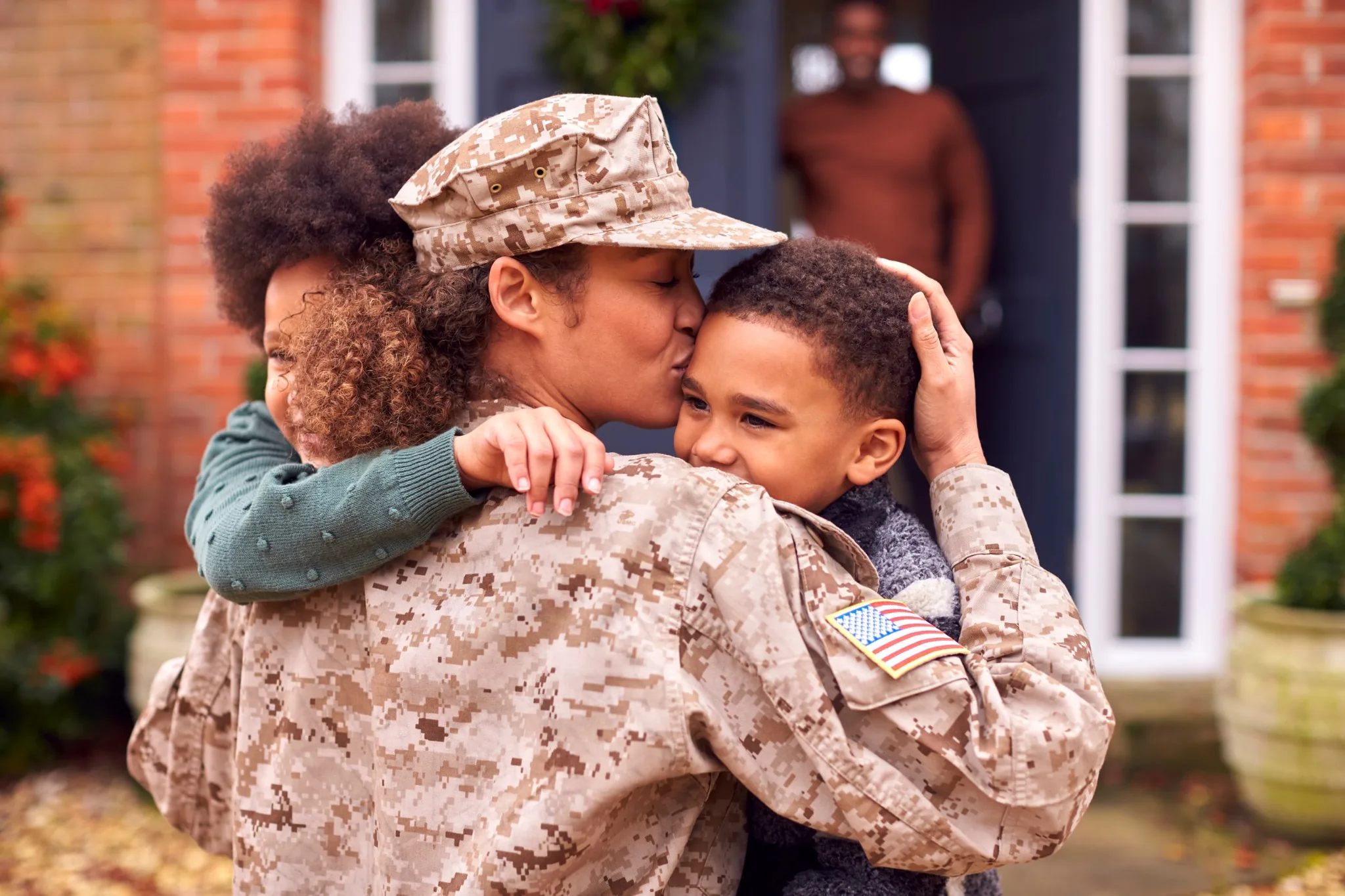 U.S. military mom hugging kids and kissing son's head