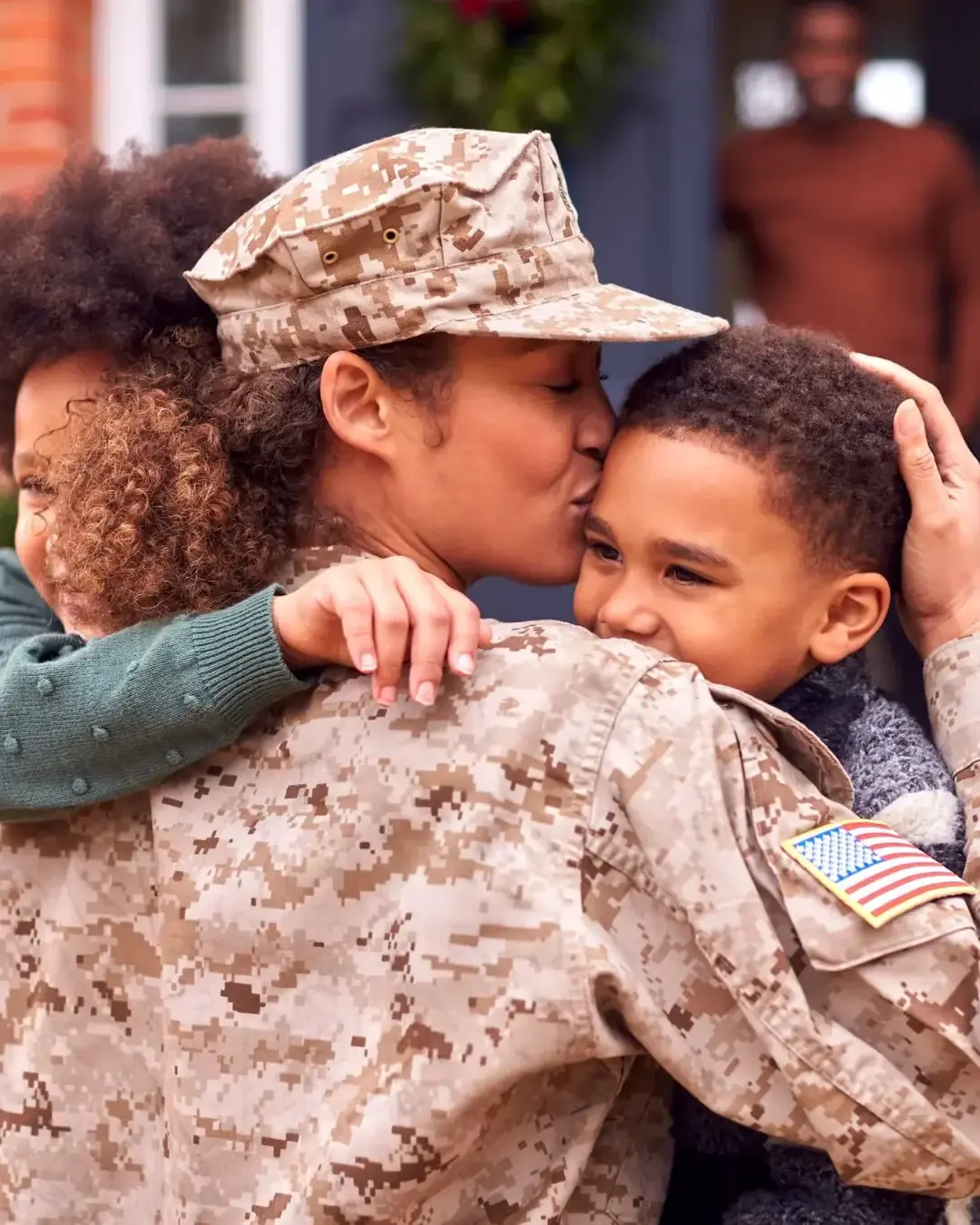 U.S. military mom hugging kids and kissing son's head