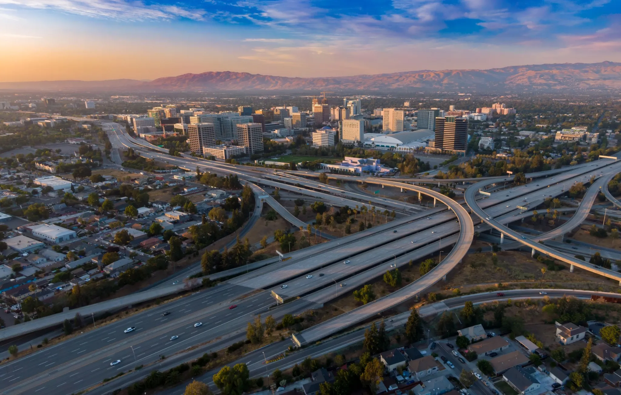 Aerial view of San Jose, California, USA, at sunset. Cars travel on the highway interchange, connecting the city's downtown with the surrounding areas. 