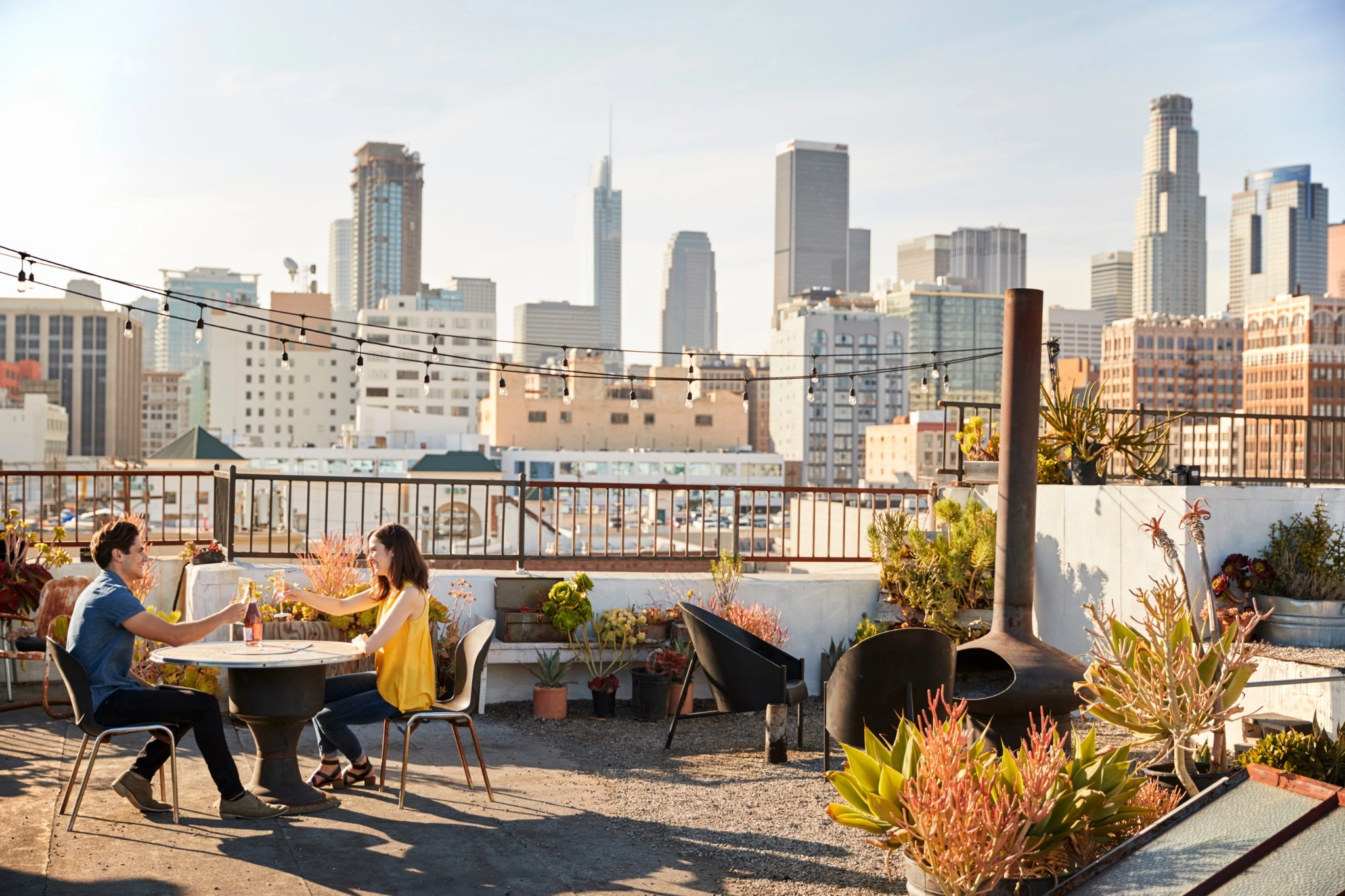 Couple cheers drinks on rooftop apartment lounge in L.A. 