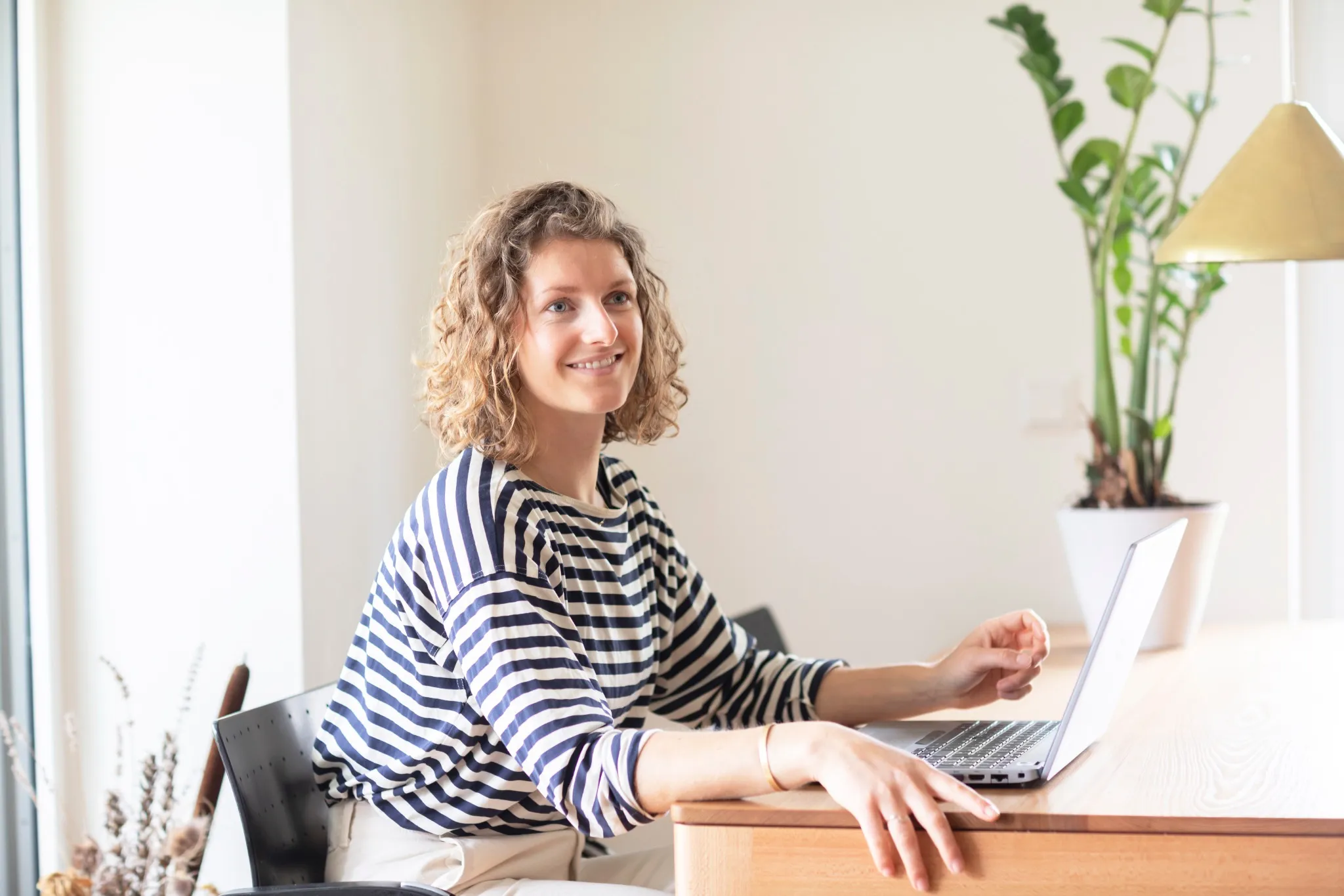 young woman sitting on a table in home office with laptop.