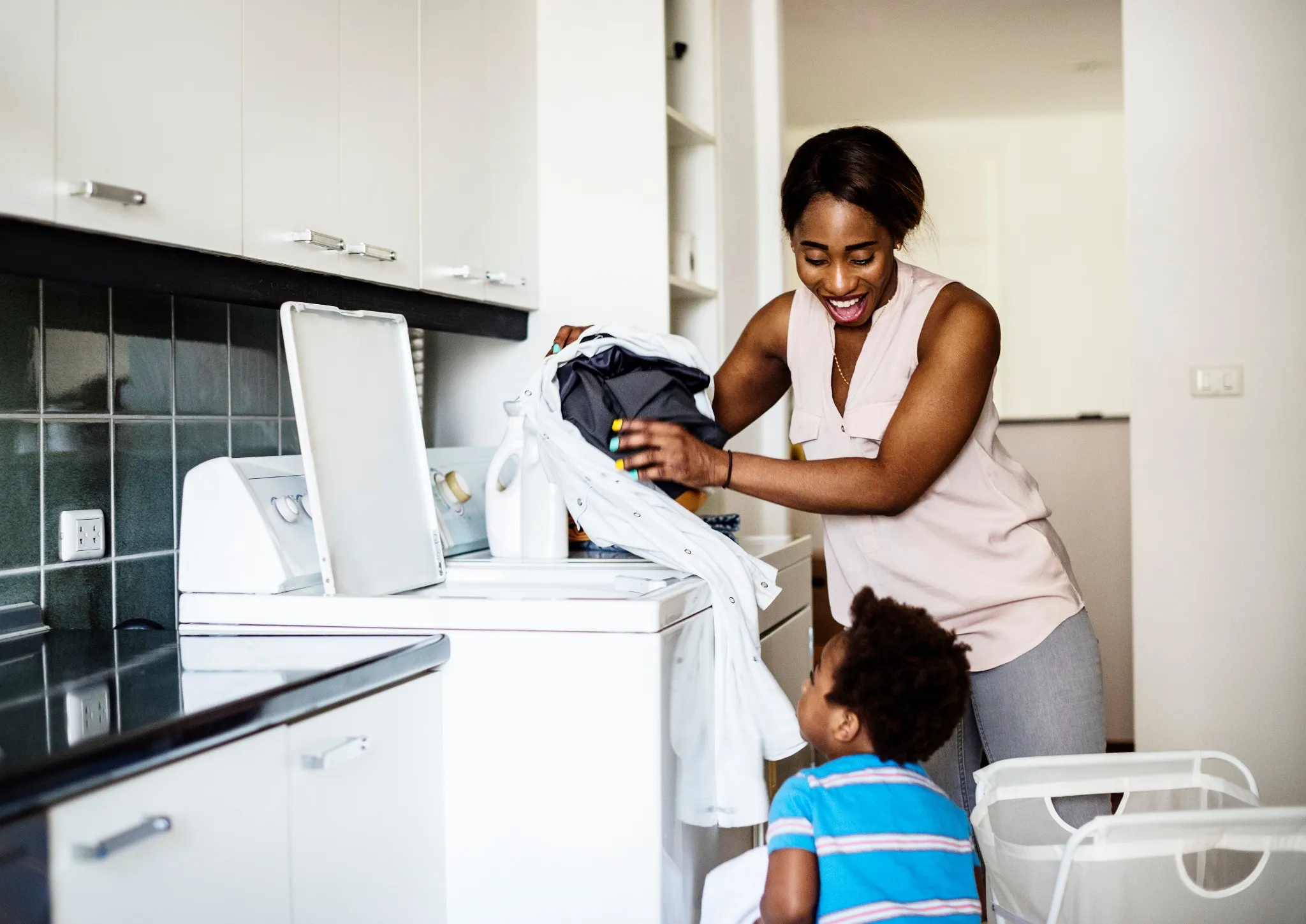 African descent kid helping mom doing the laundry