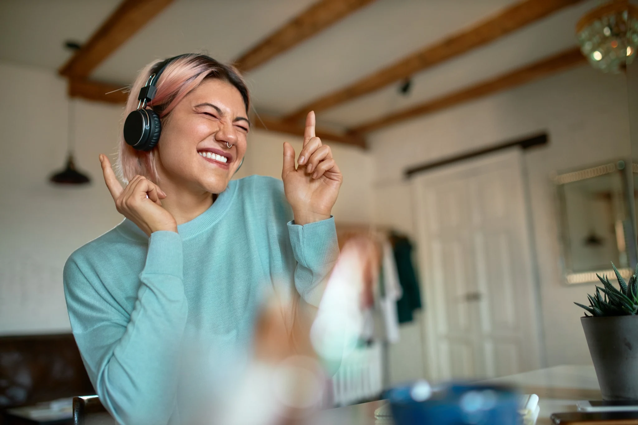 Creative looking woman wearing headphones dancing in chair at home