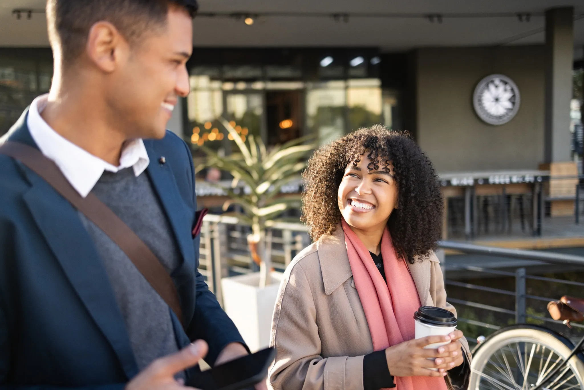 Communication, coffee break and happy business people walking, talking or travel in San Francisco. Architecture, black woman or employee partnership team on morning commute journey to office building
