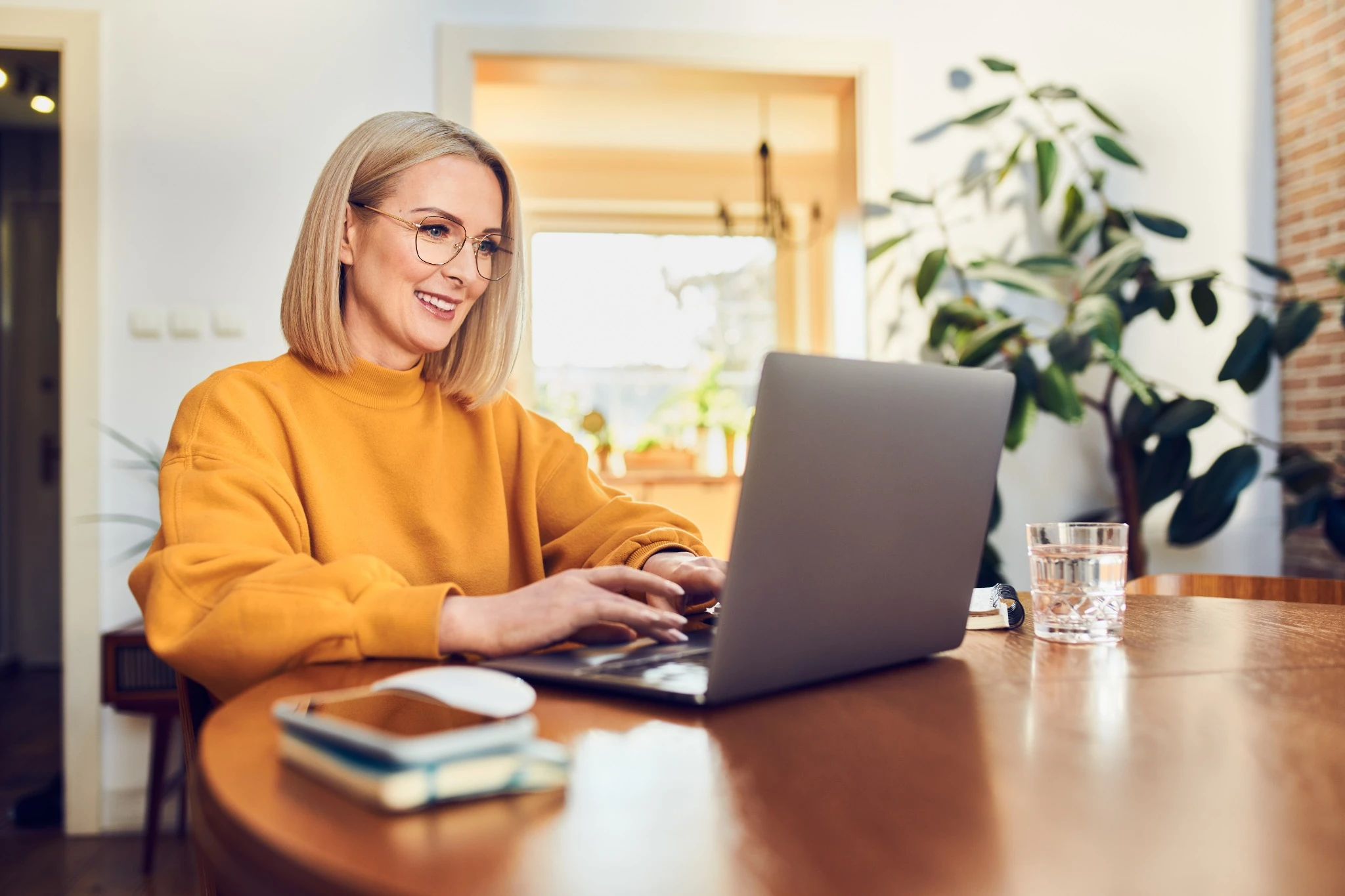 Portrait of middle aged woman sitting at dinning with laptop
