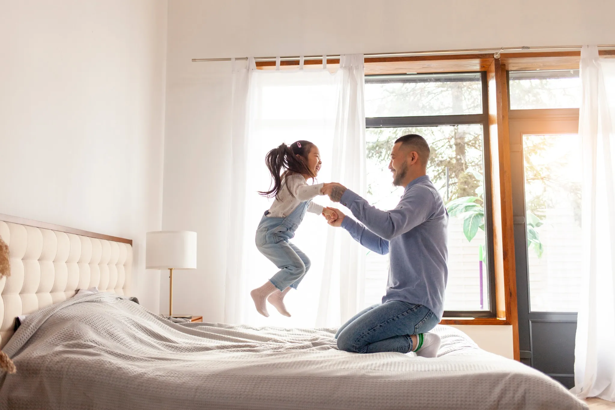 dad with little girl jumping on bed