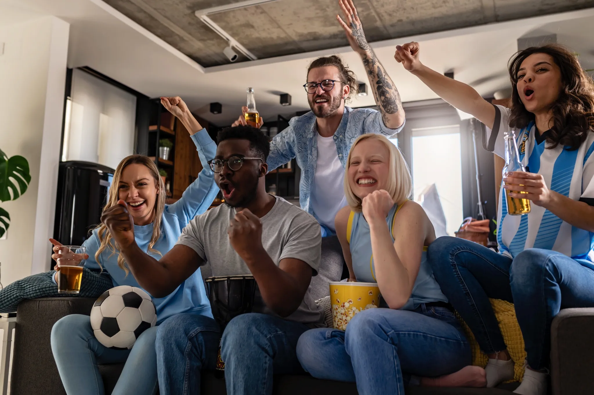 Excited multicultural football fans celebrate a goal score of their team.
