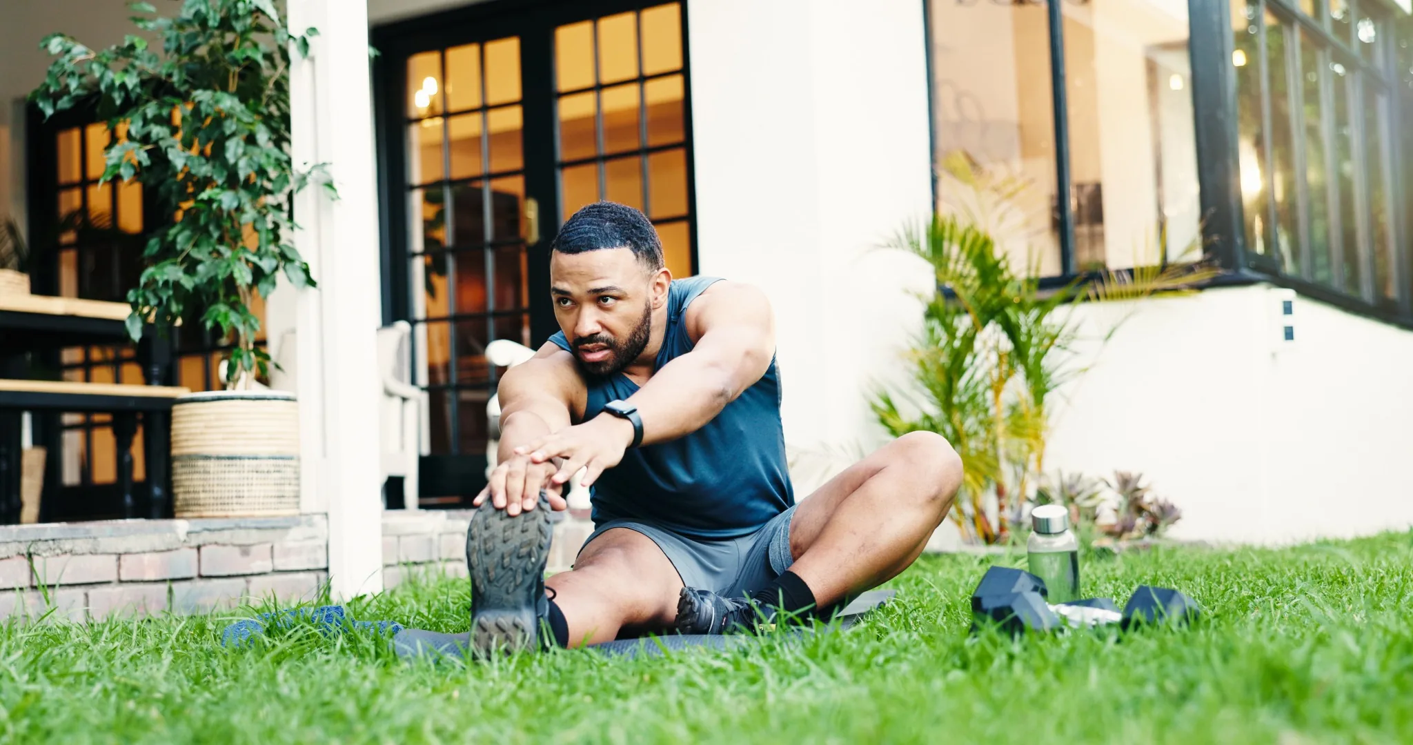 Man in athletic clothes stretching in lawn after workout at home