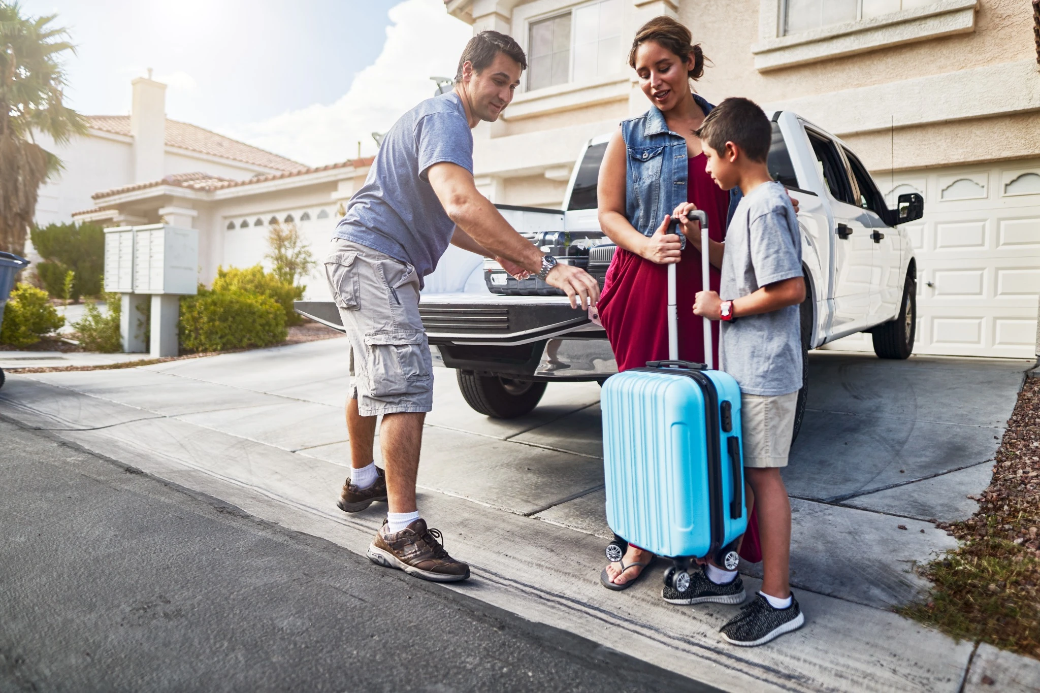 hispanic family packing luggage into pickup truck in front of house.