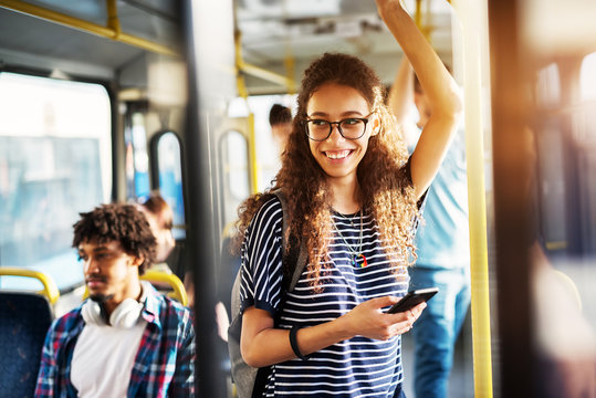 Young woman standing and smiling on public transit