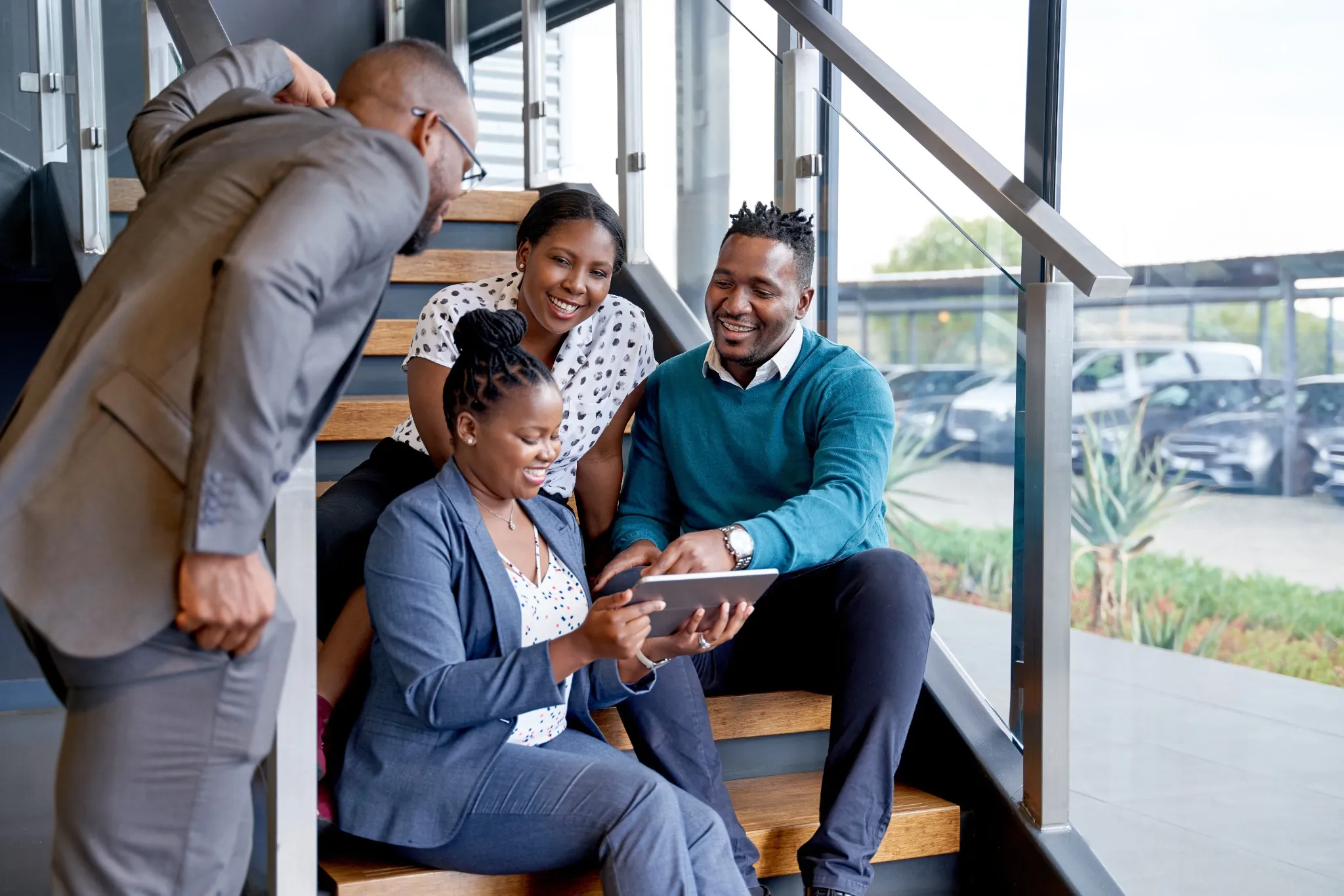 Four professional male and female coworkers sitting on staircase.