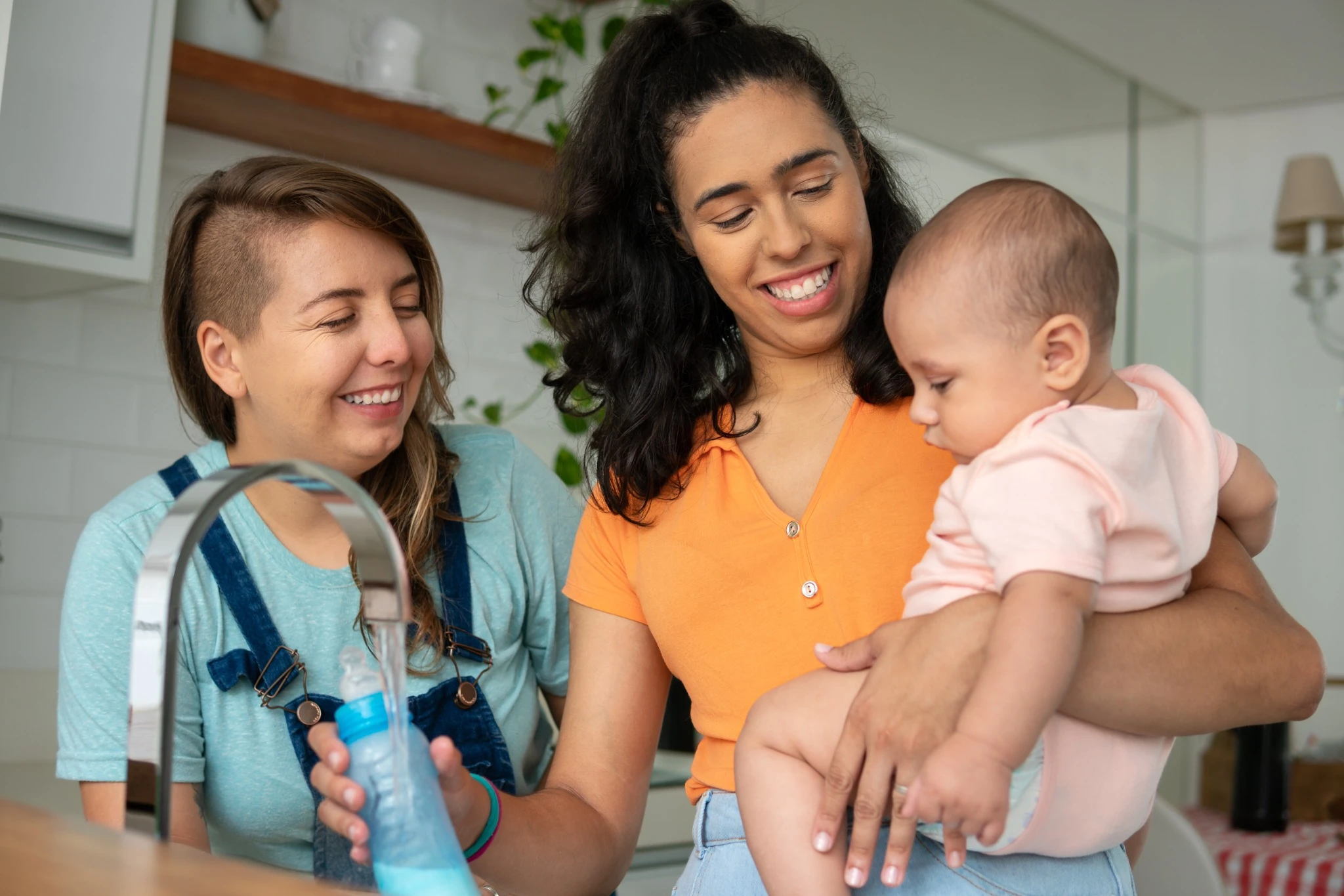 same sex couple cooling the milk bottle of the baby in the kitchen..