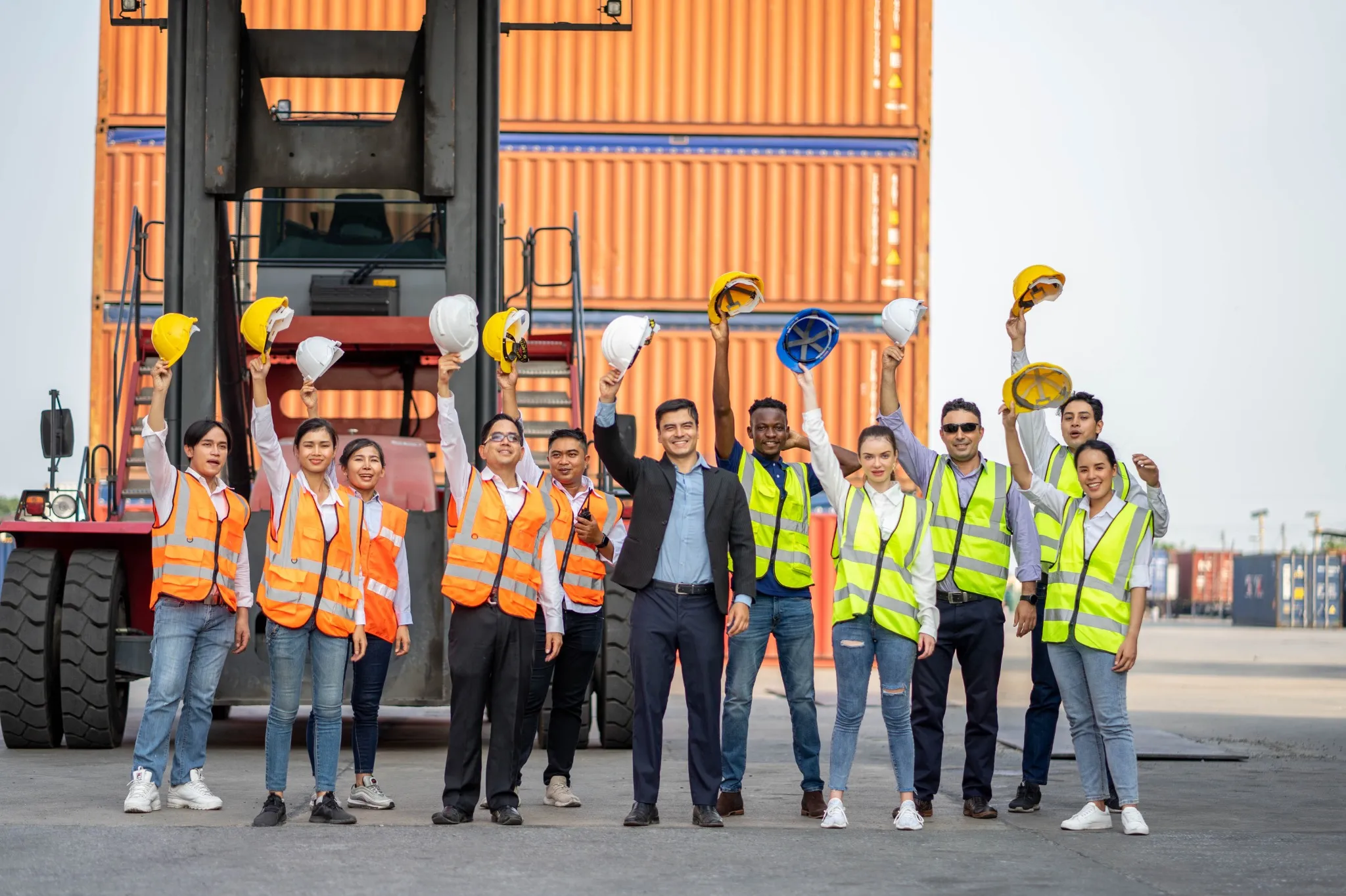 Group of employees and management team wearing logistic uniforms and stand to celebrating or raise their hands together for exporting products abroad. Finishing successful..