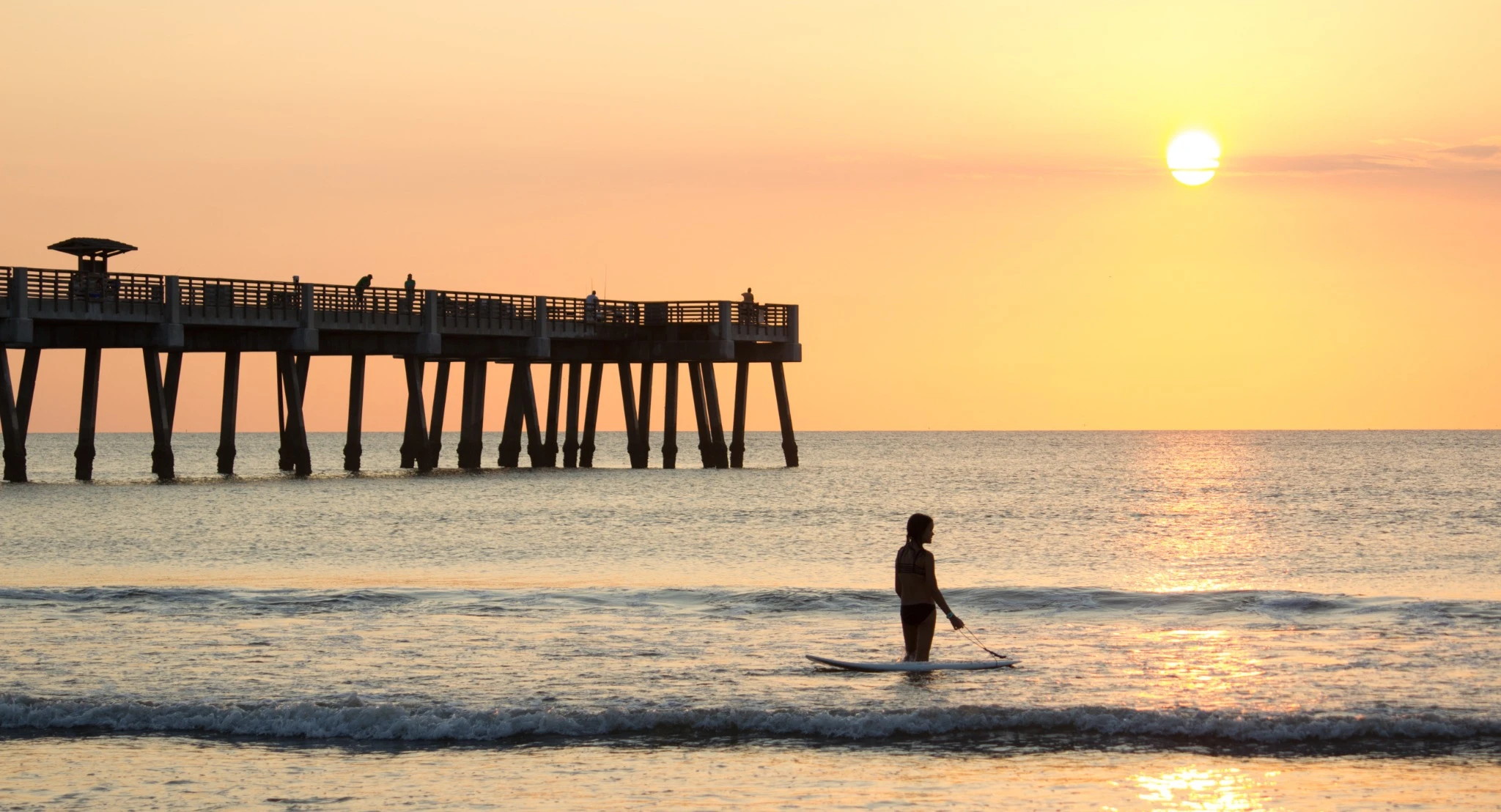 Girl paddleboarding at sunset.