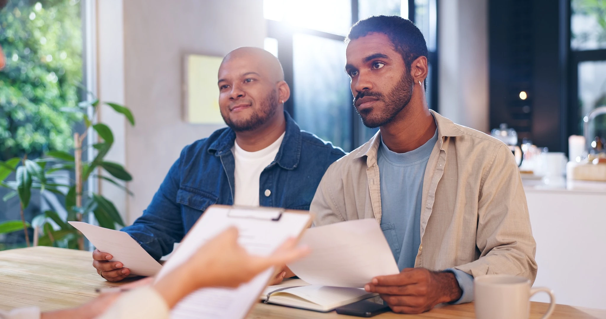 Img - two men sitting on the couch discussing paperwork with another person