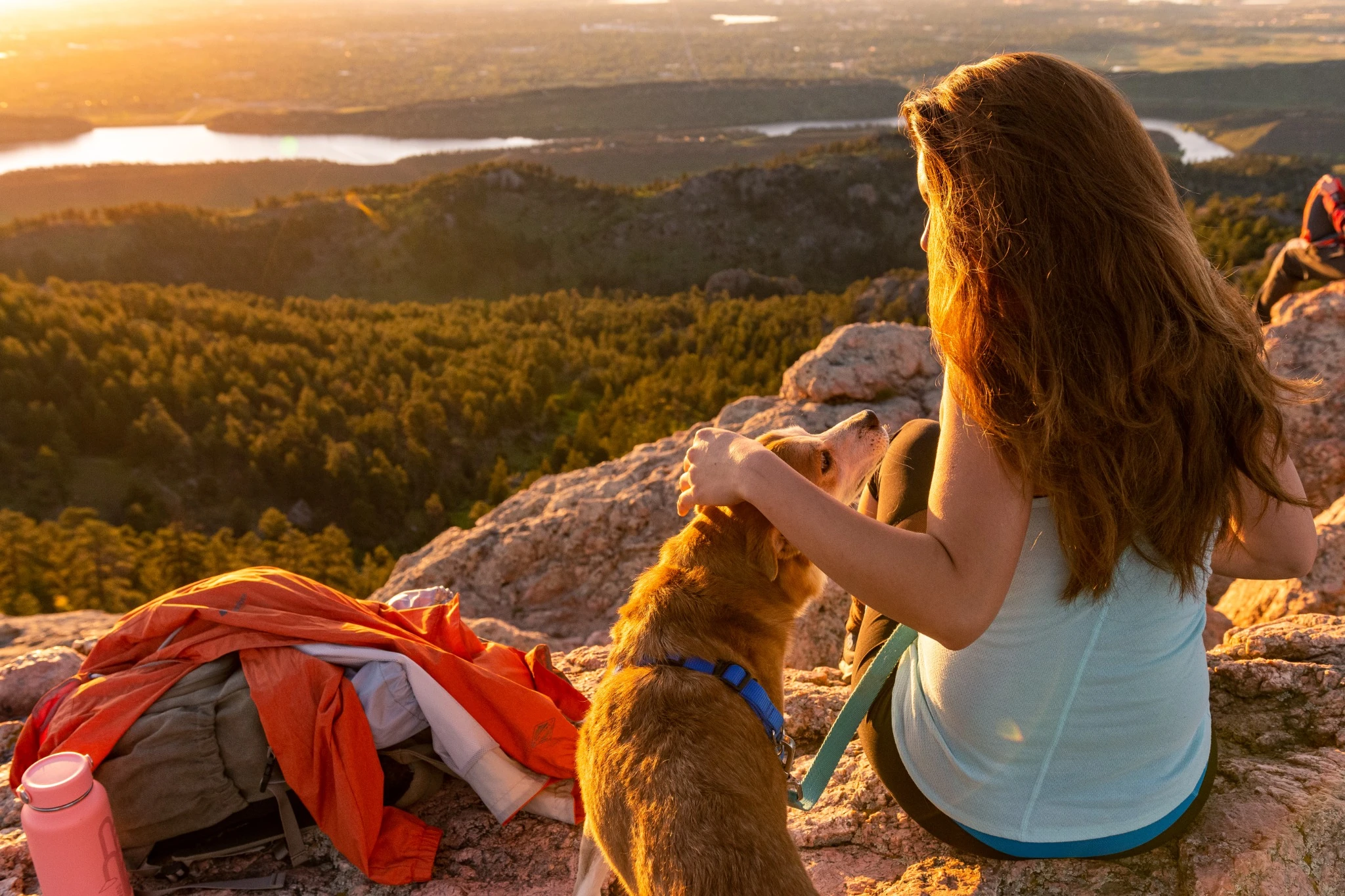 girl with her dog during the sunrise over the Rocky Mountains.