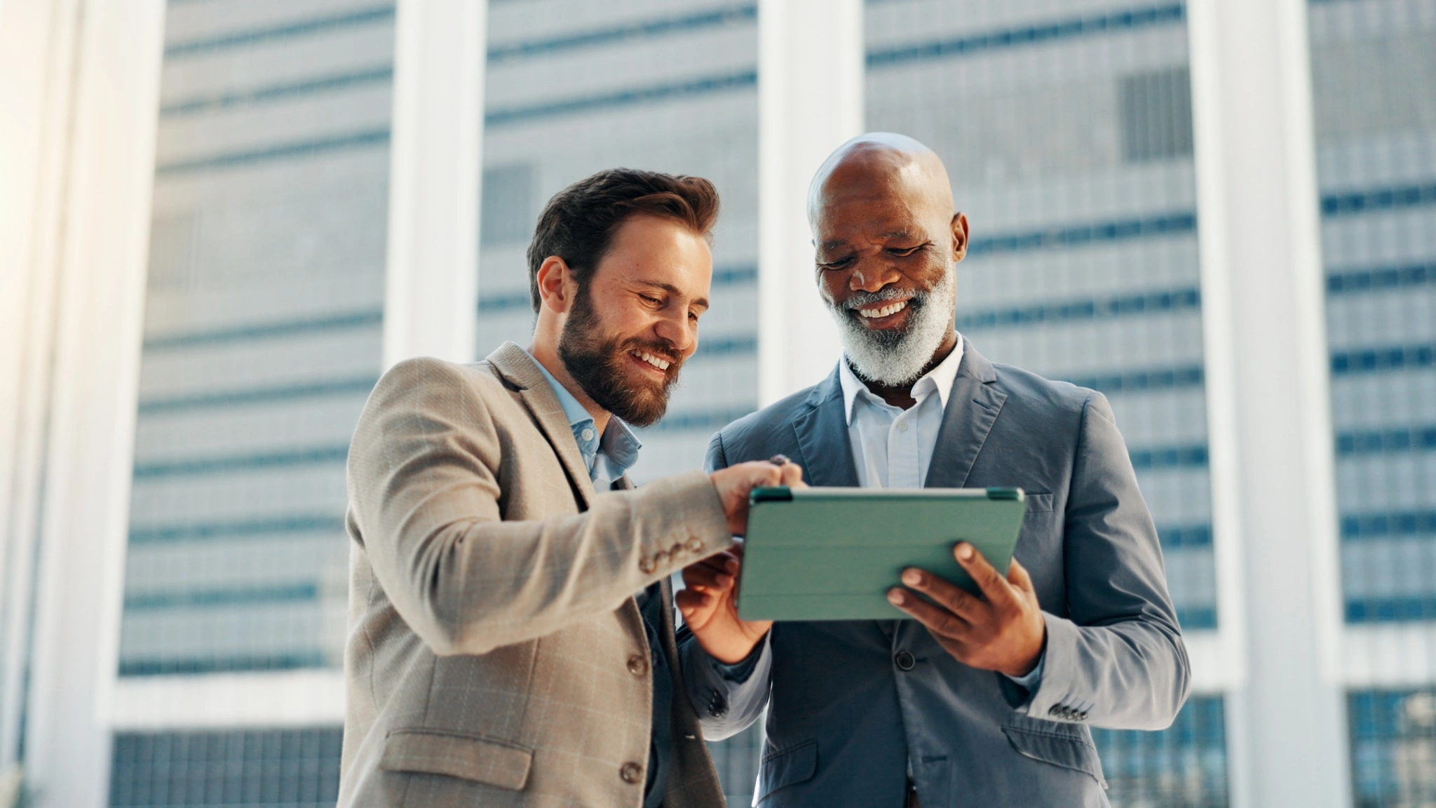 Two businessmen looking at tablet with high rises in the background