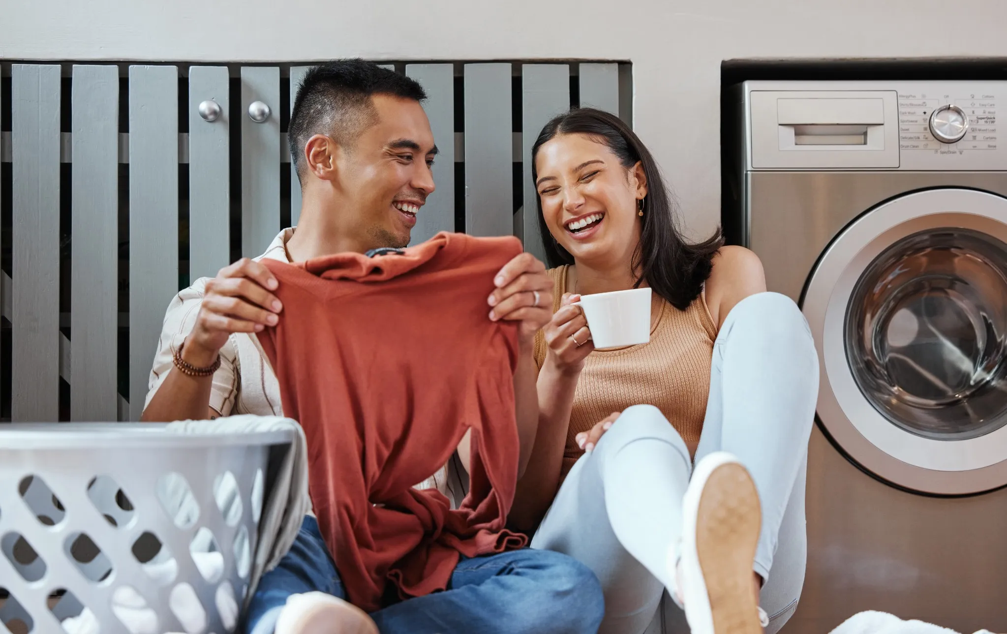 couple sitting on floor doing laundry and laughing