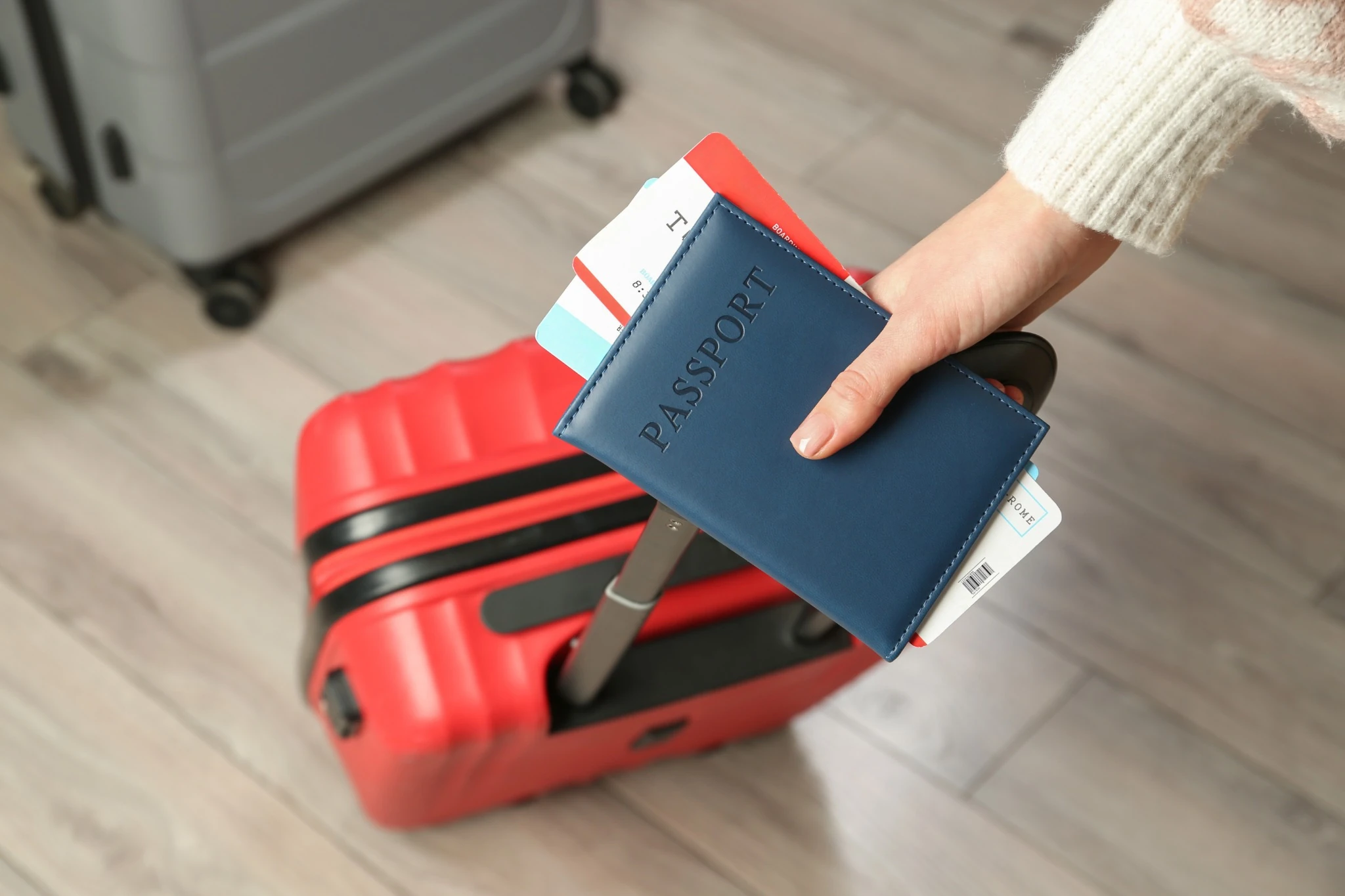 red rolling suitcase, passport, and other documents