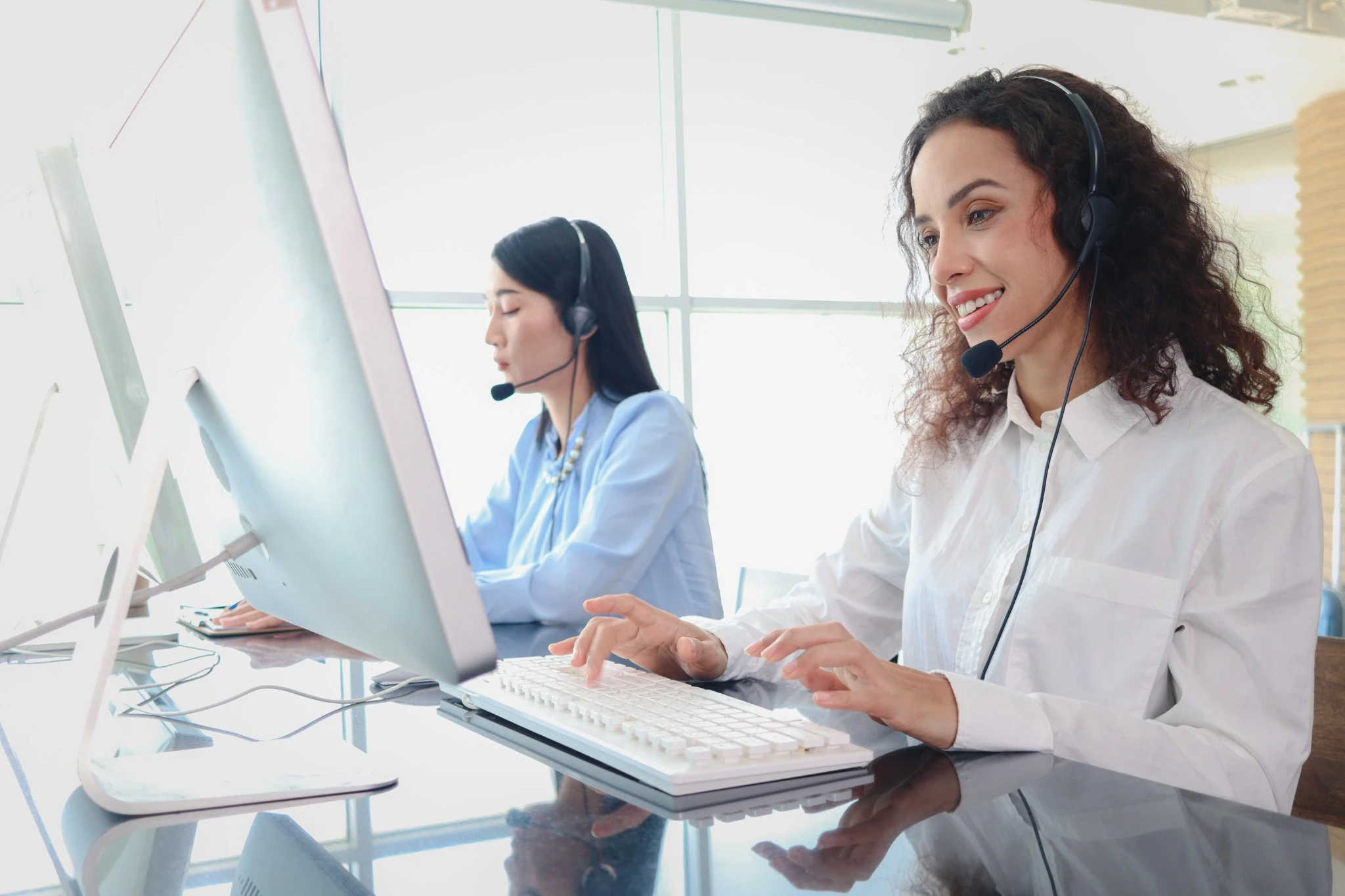 Two friendly women with headsets supporting customers