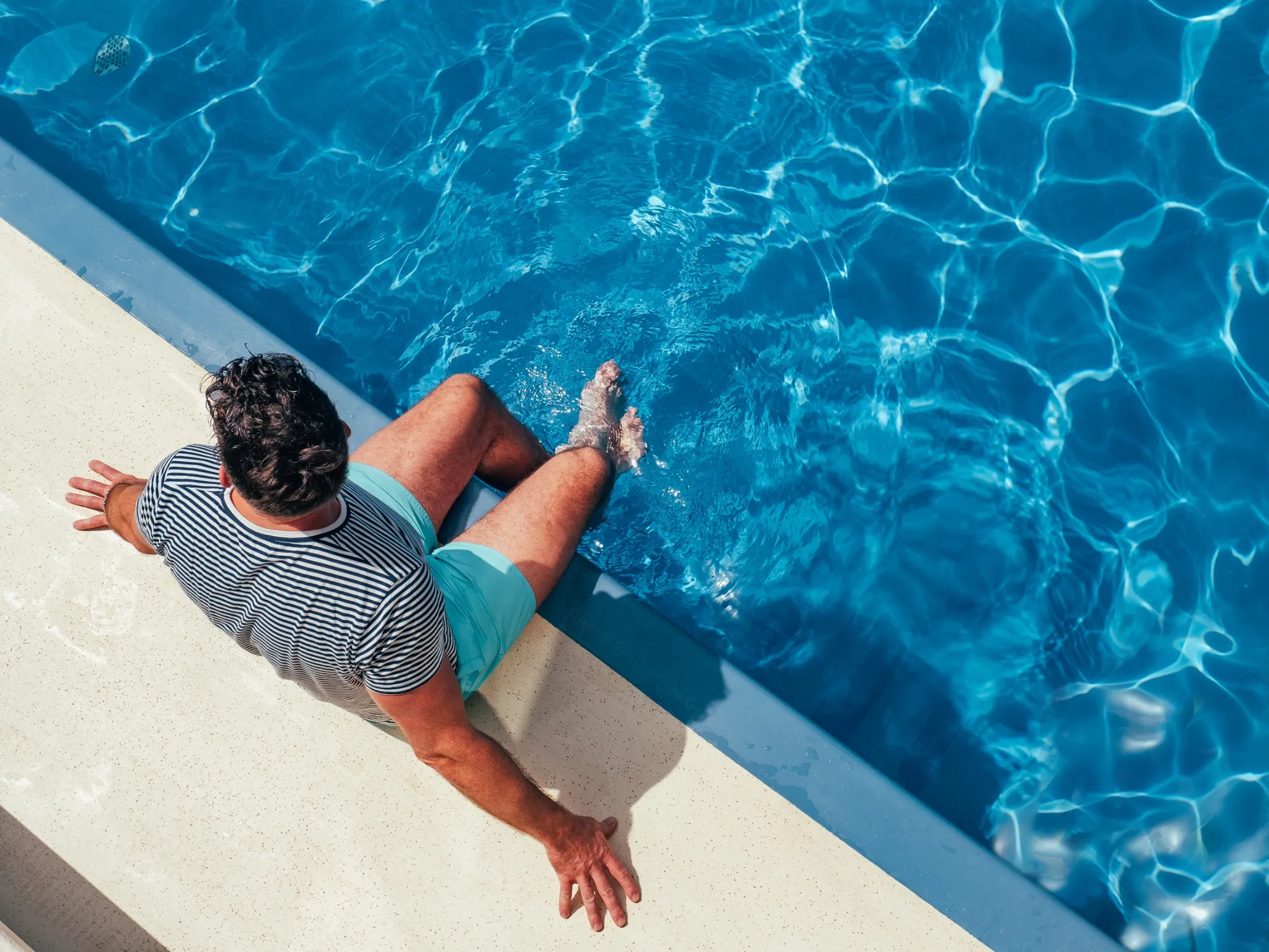 Man sitting at edge of the pool with feet in